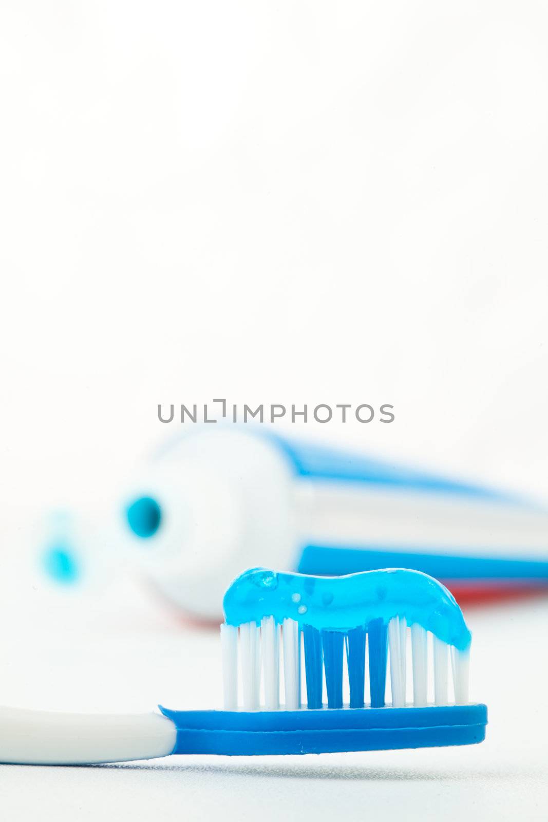 Toothpaste next to a toothbrush against white background
