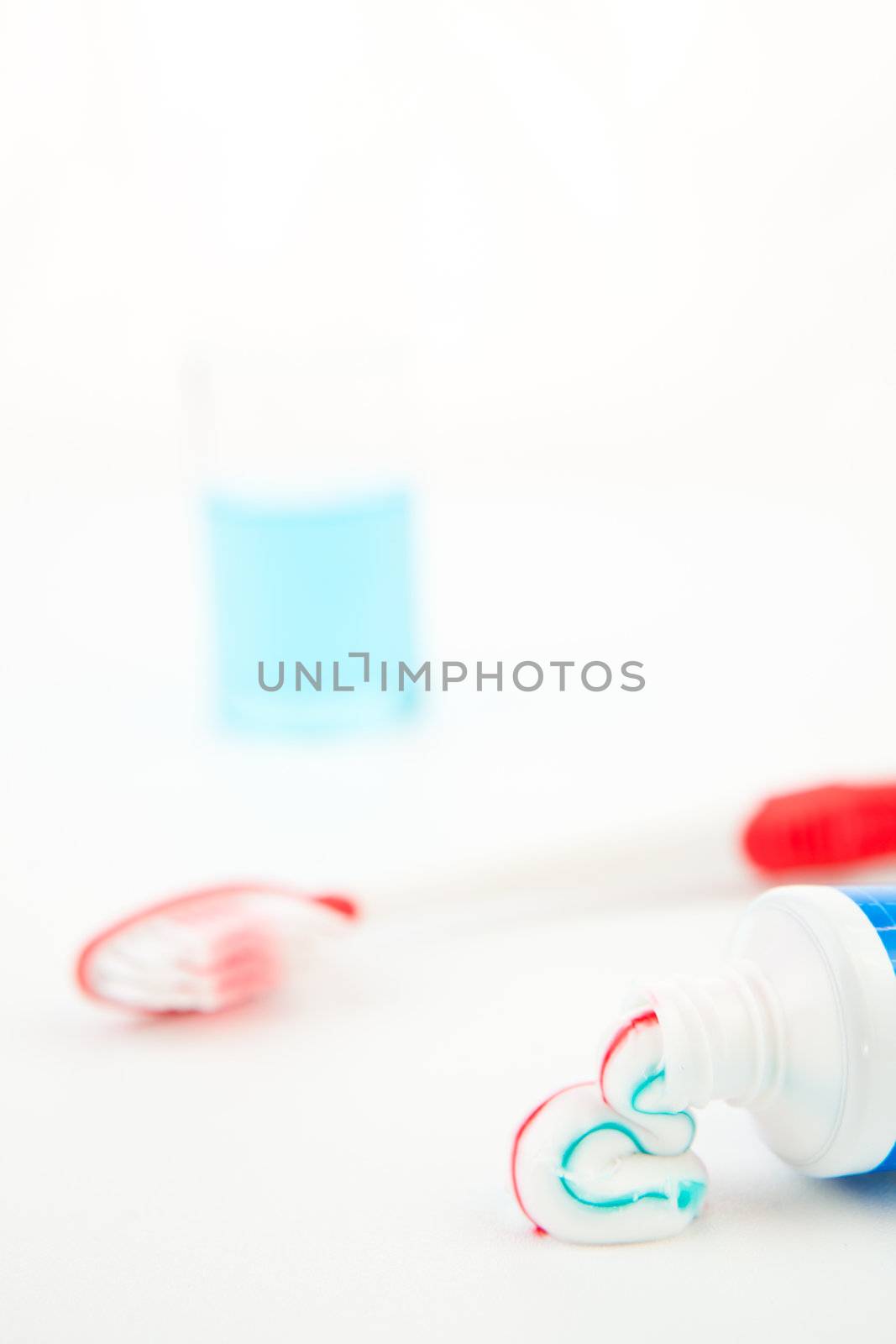 Red toothbrush next to a glass against white background