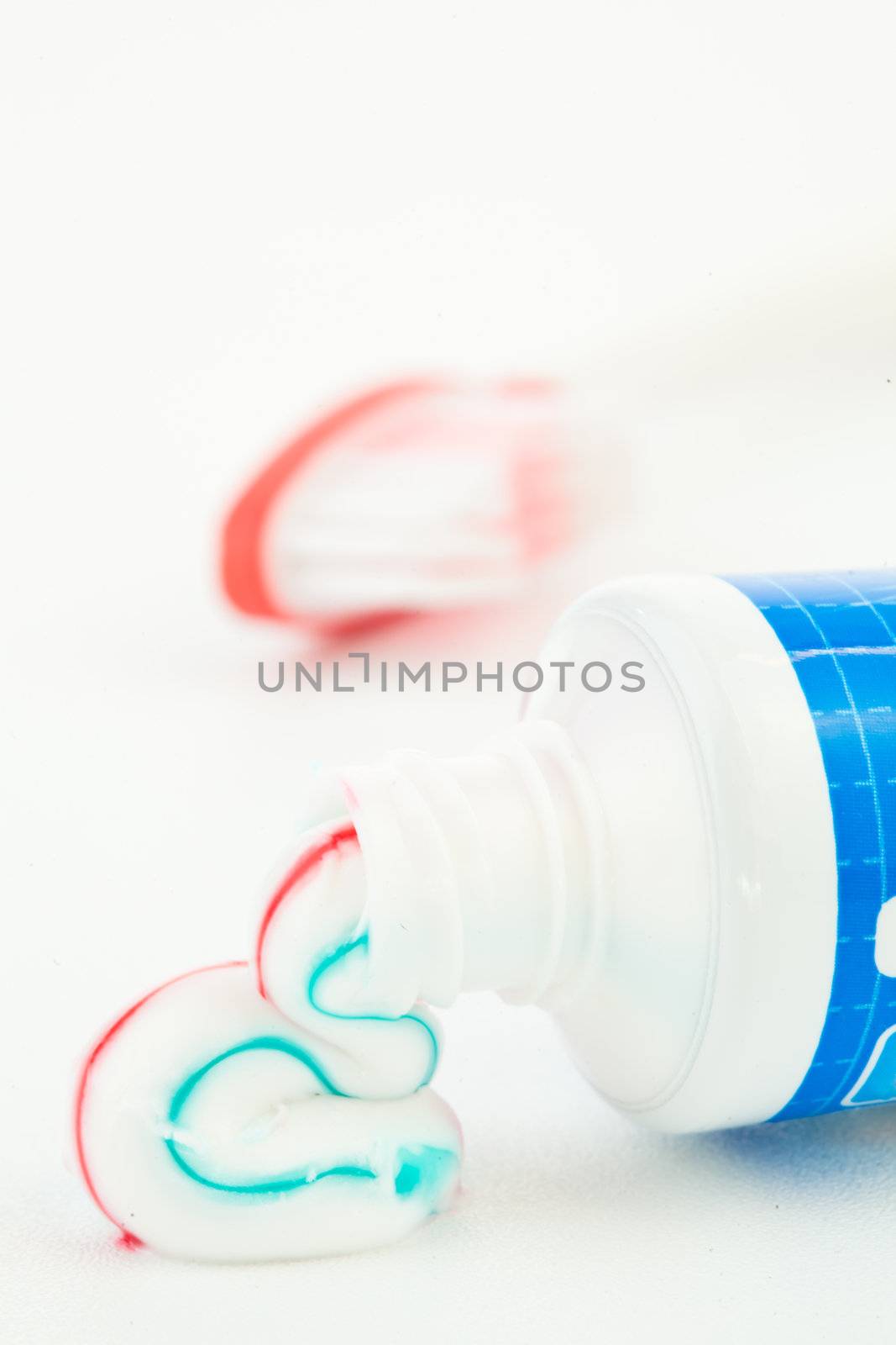 Blue tube of toothpaste next to a toothbrush against white background