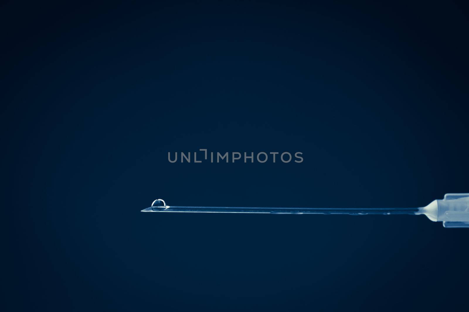 Liquid outgoing of a needle against a blue background