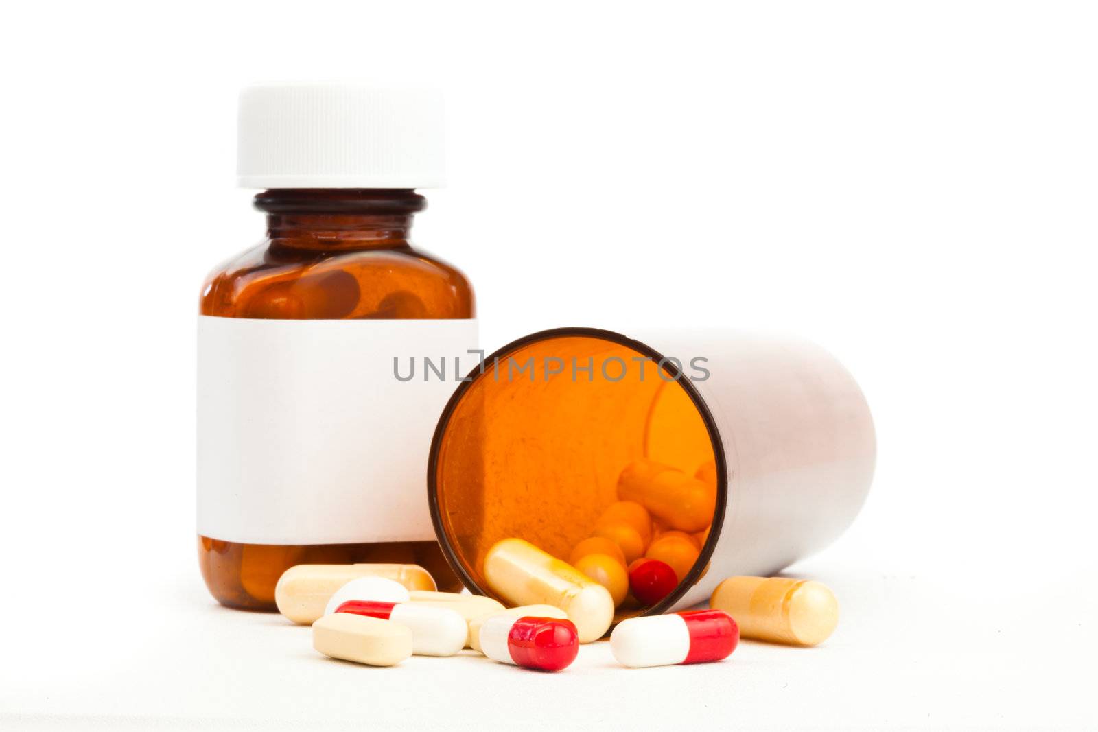 Glass bottle of capsules knocked over against a white background