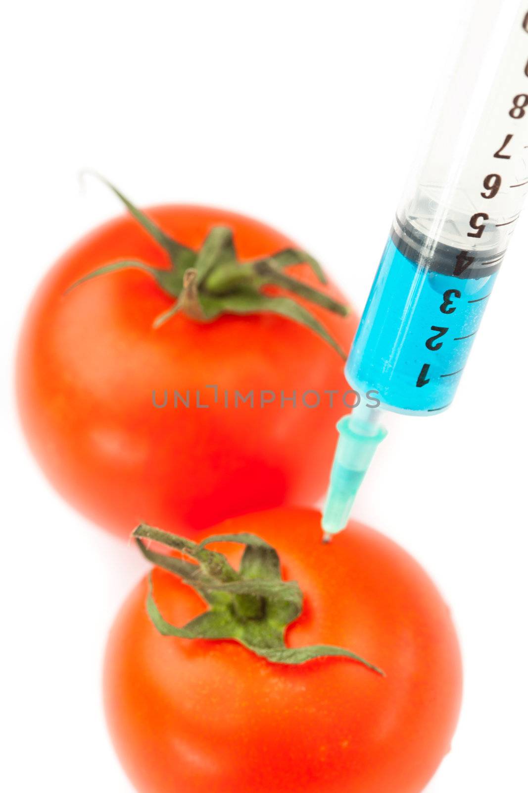 Syringe pricking a tomato against a white background