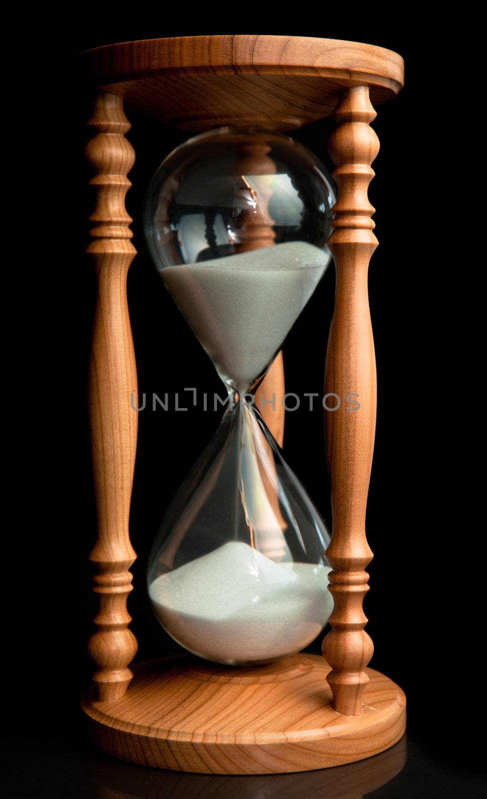 Sand flowing inside of hourglass against a black background