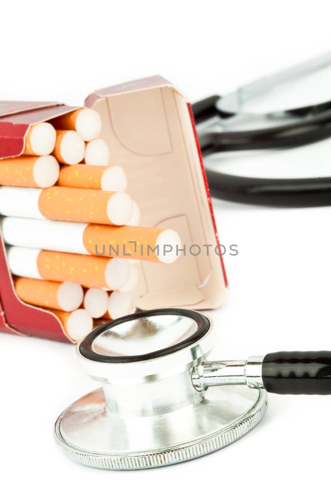 Cigarette pack next to a stethoscope against a white background