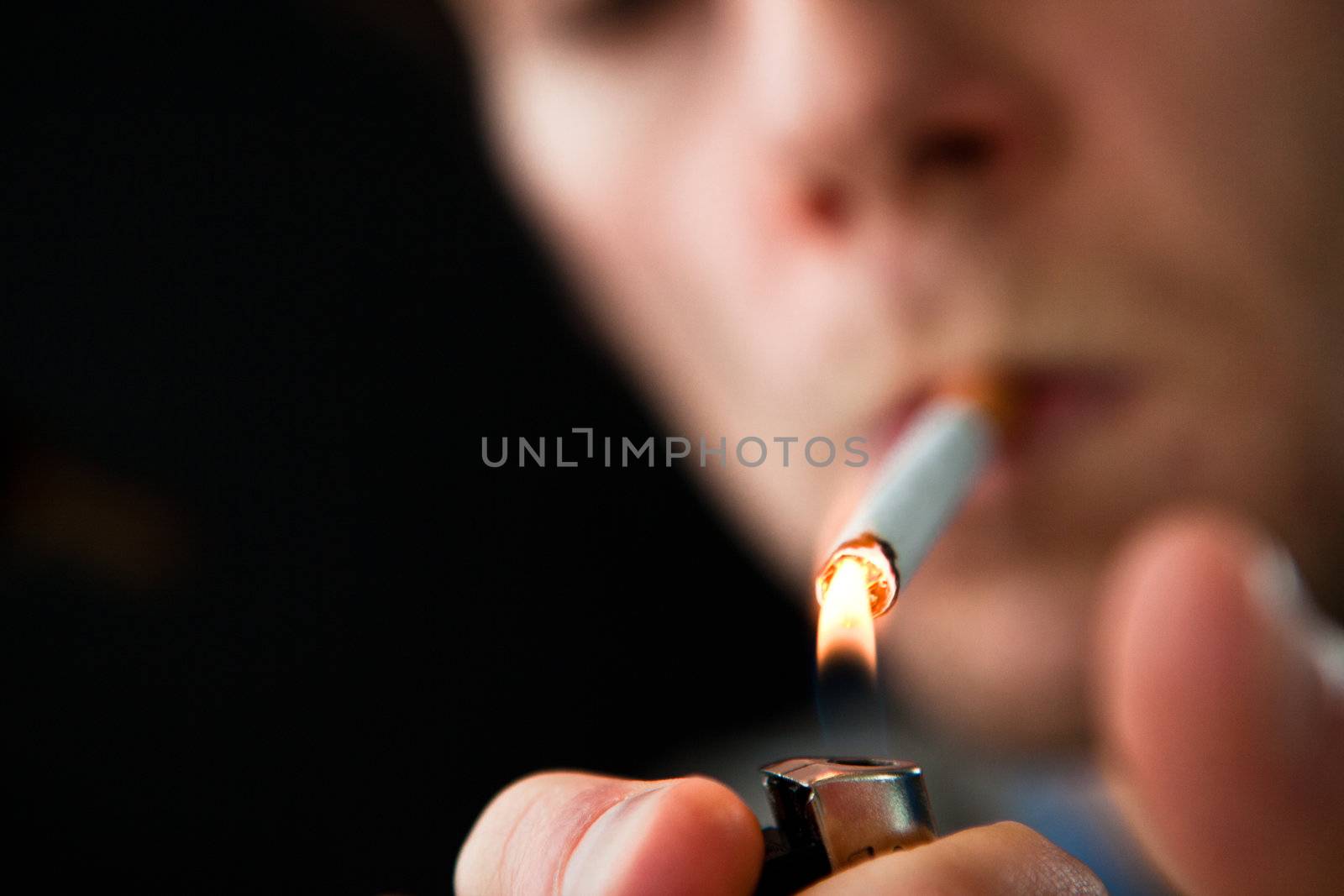 Man lighting a cigarette against a black background