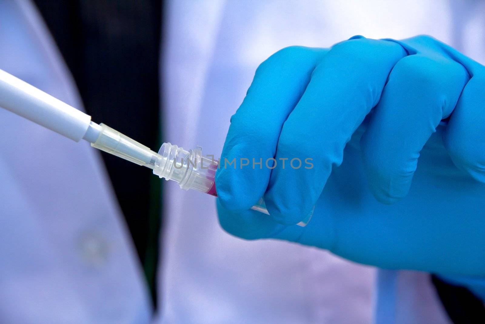 Pipette with drop of liquid in a science research lab