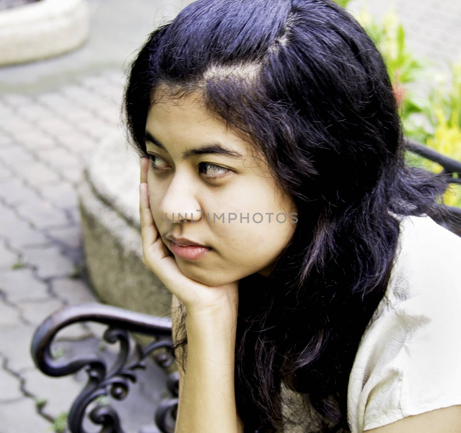 Teenage girl sitting on bench in public park