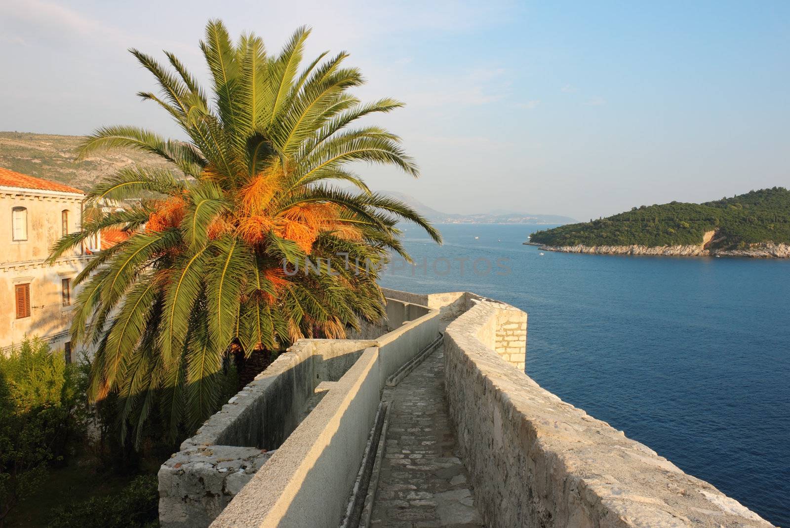 Walk around Dubrovnik Fortress wall, with a view toward island Lokrum in the warm light of the sunset.