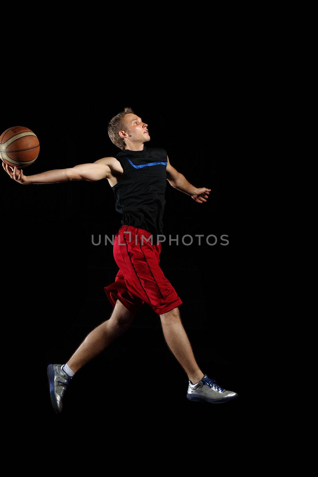 Male basketball player jumping and practicing with a ball