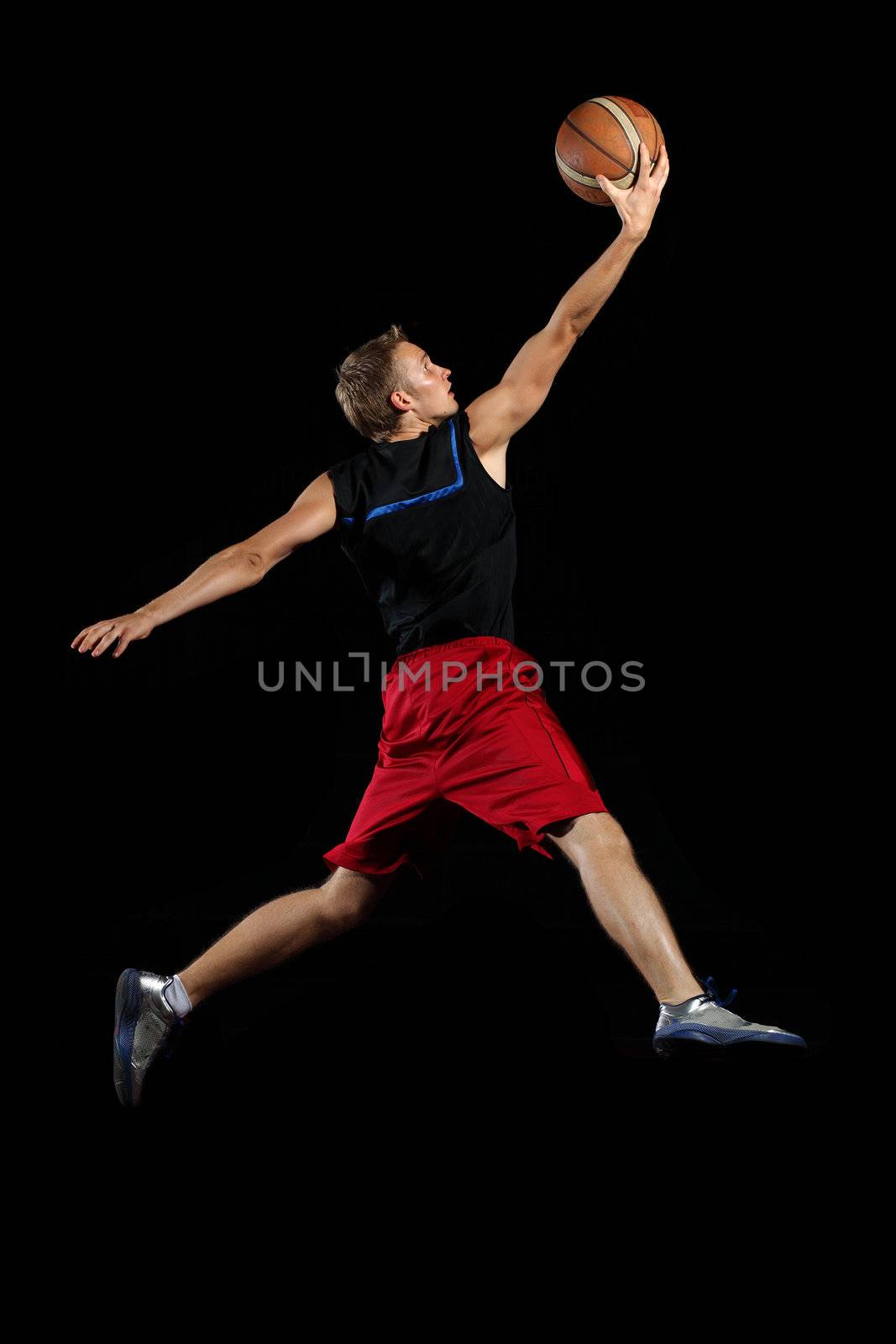 Male basketball player jumping and practicing with a ball