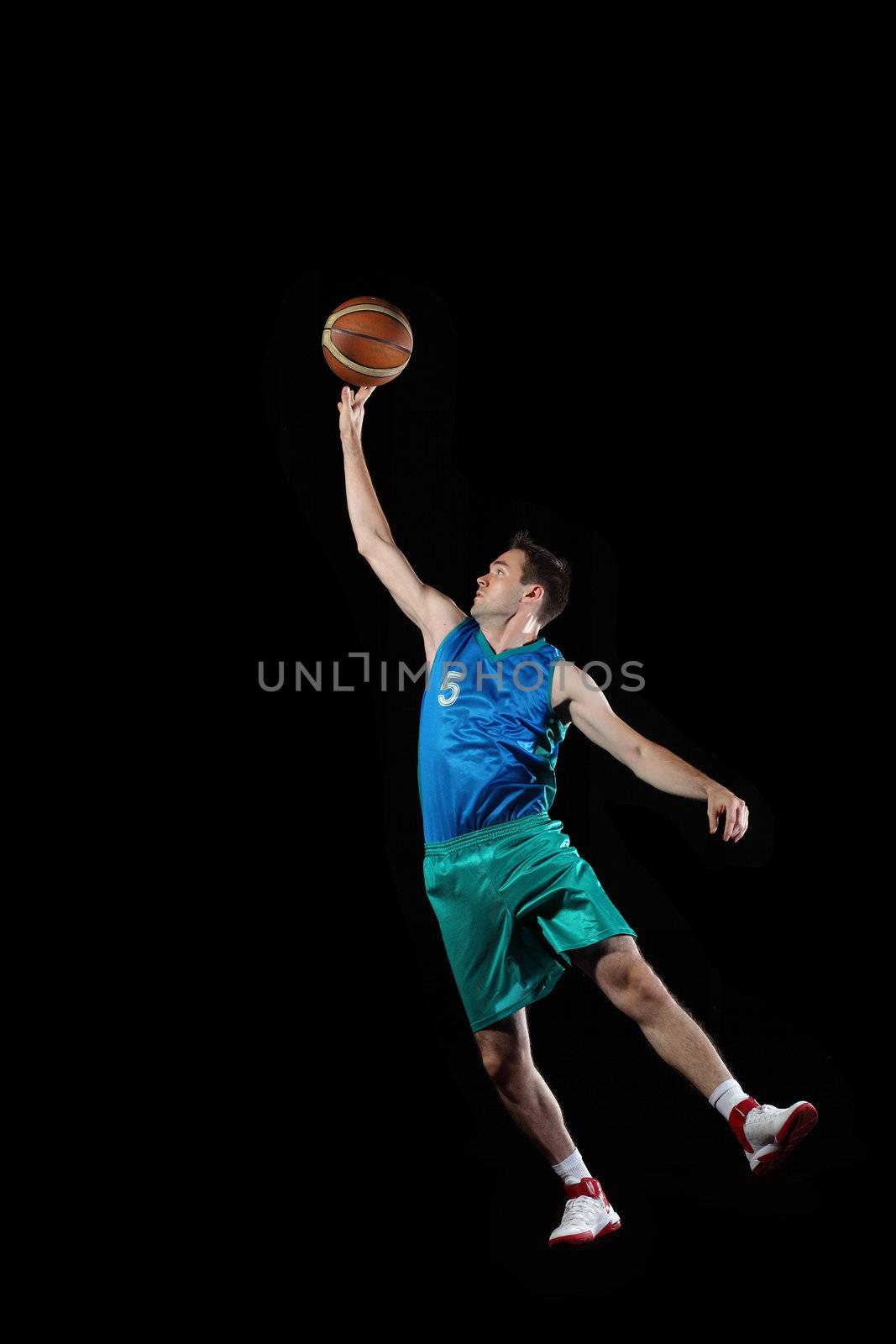 Male basketball player jumping and practicing with a ball