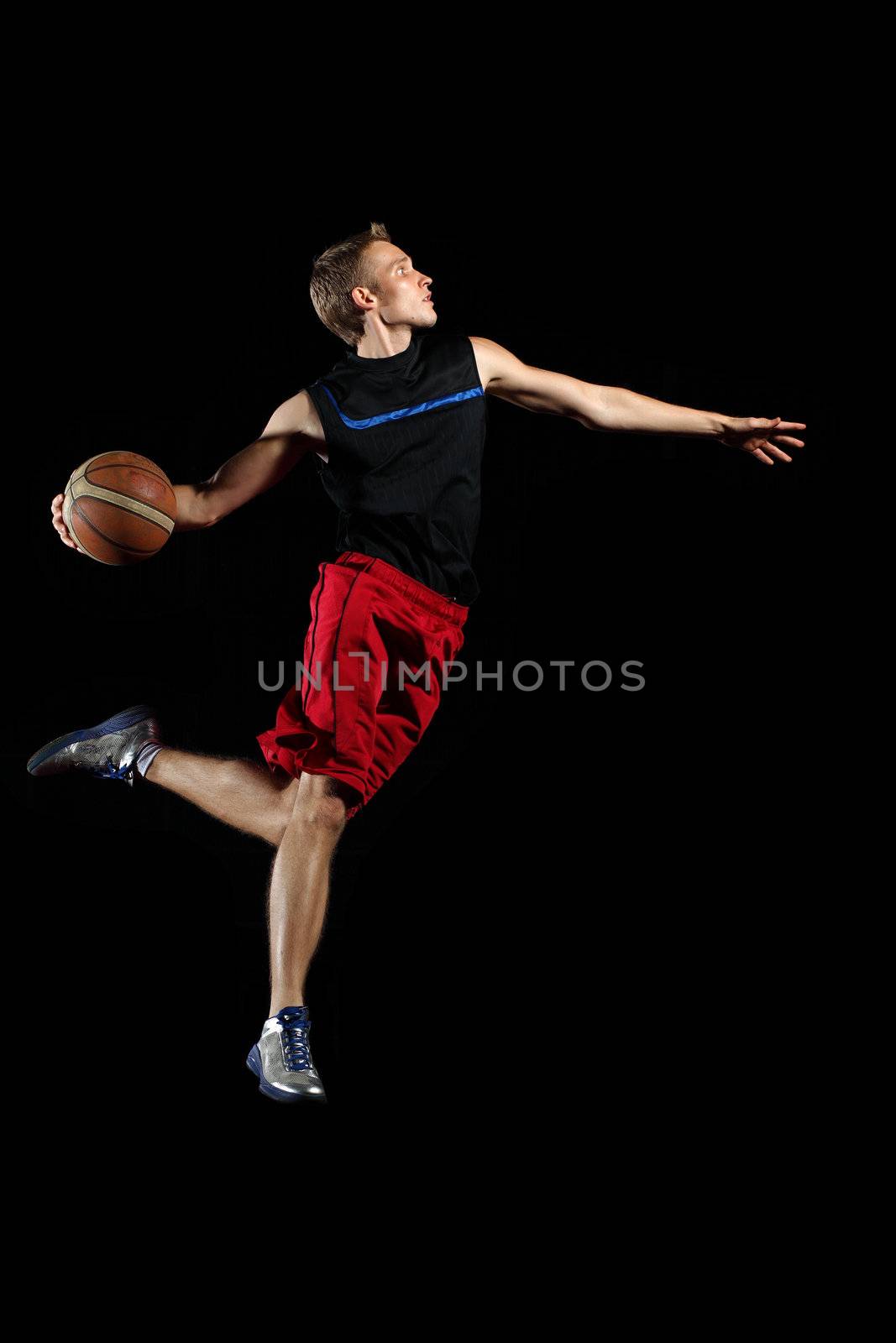 Male basketball player jumping and practicing with a ball
