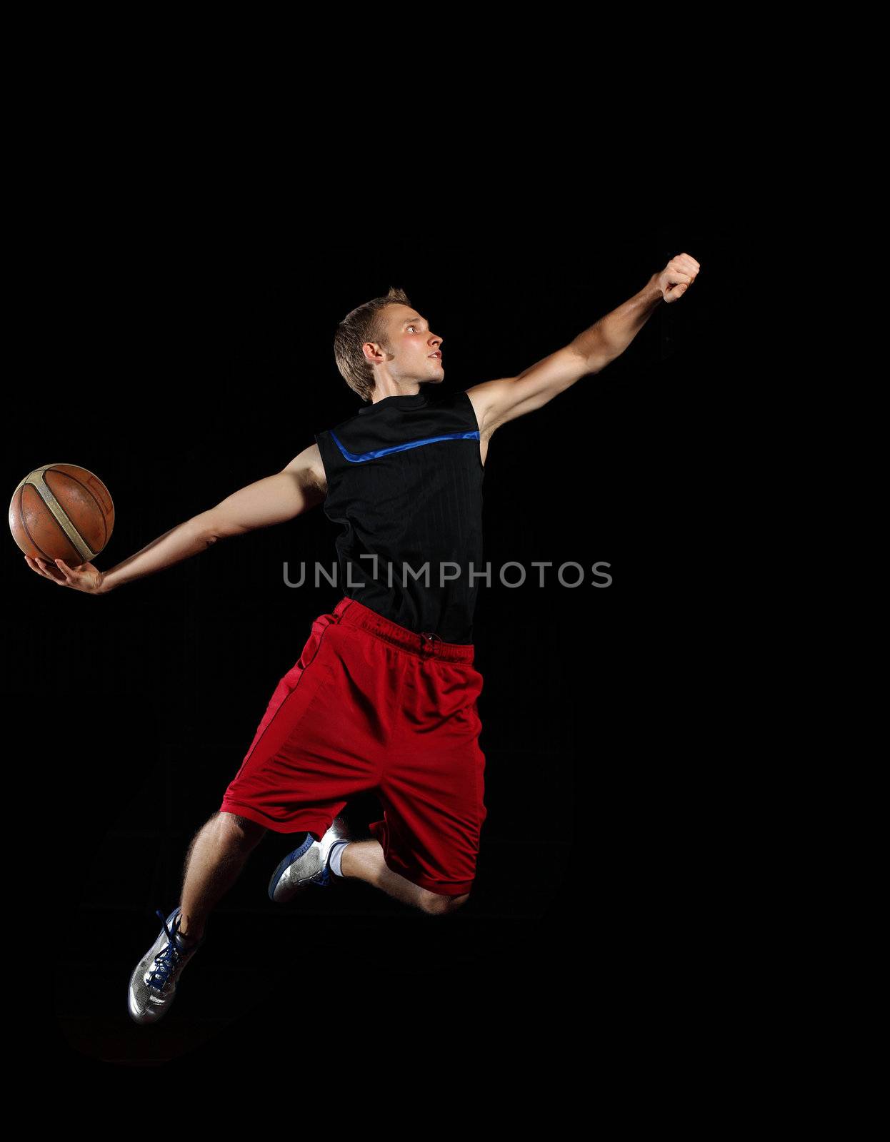 Male basketball player jumping and practicing with a ball