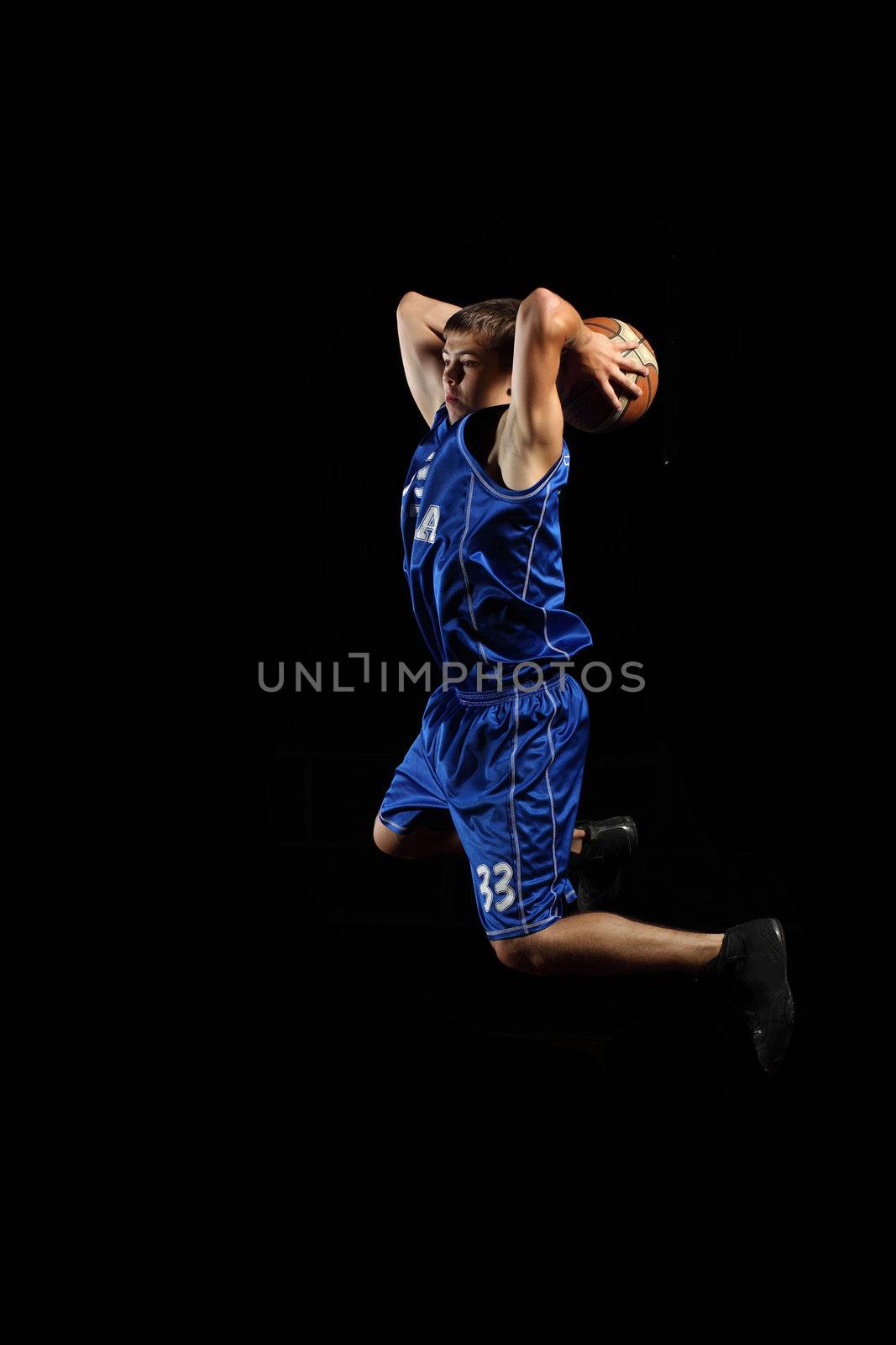 Male basketball player jumping and practicing with a ball