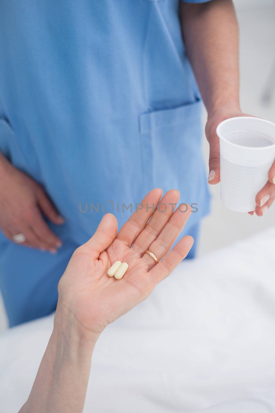 Nurse giving plastic glass to a patient by Wavebreakmedia