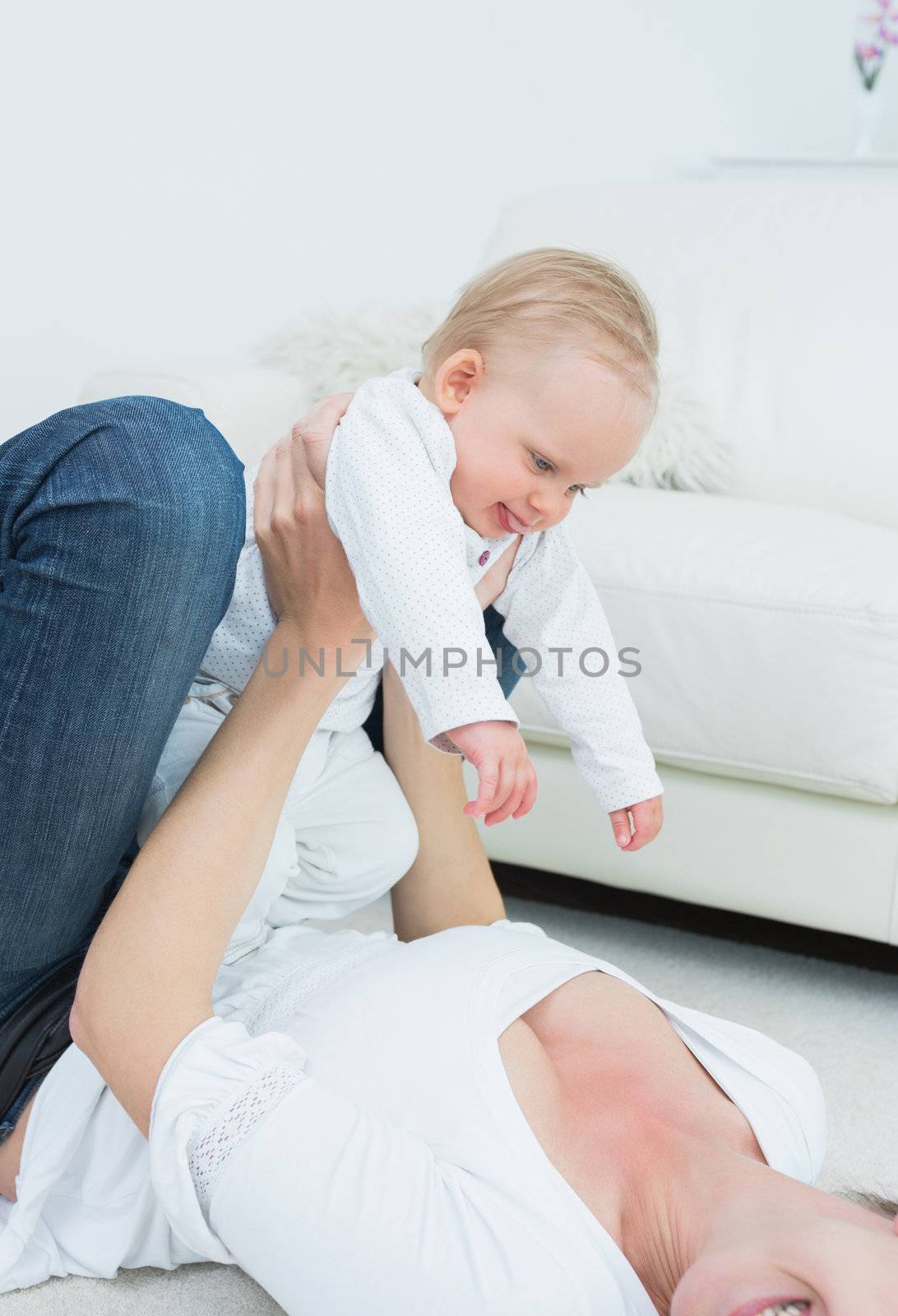 Mother lying while holding a baby in living room