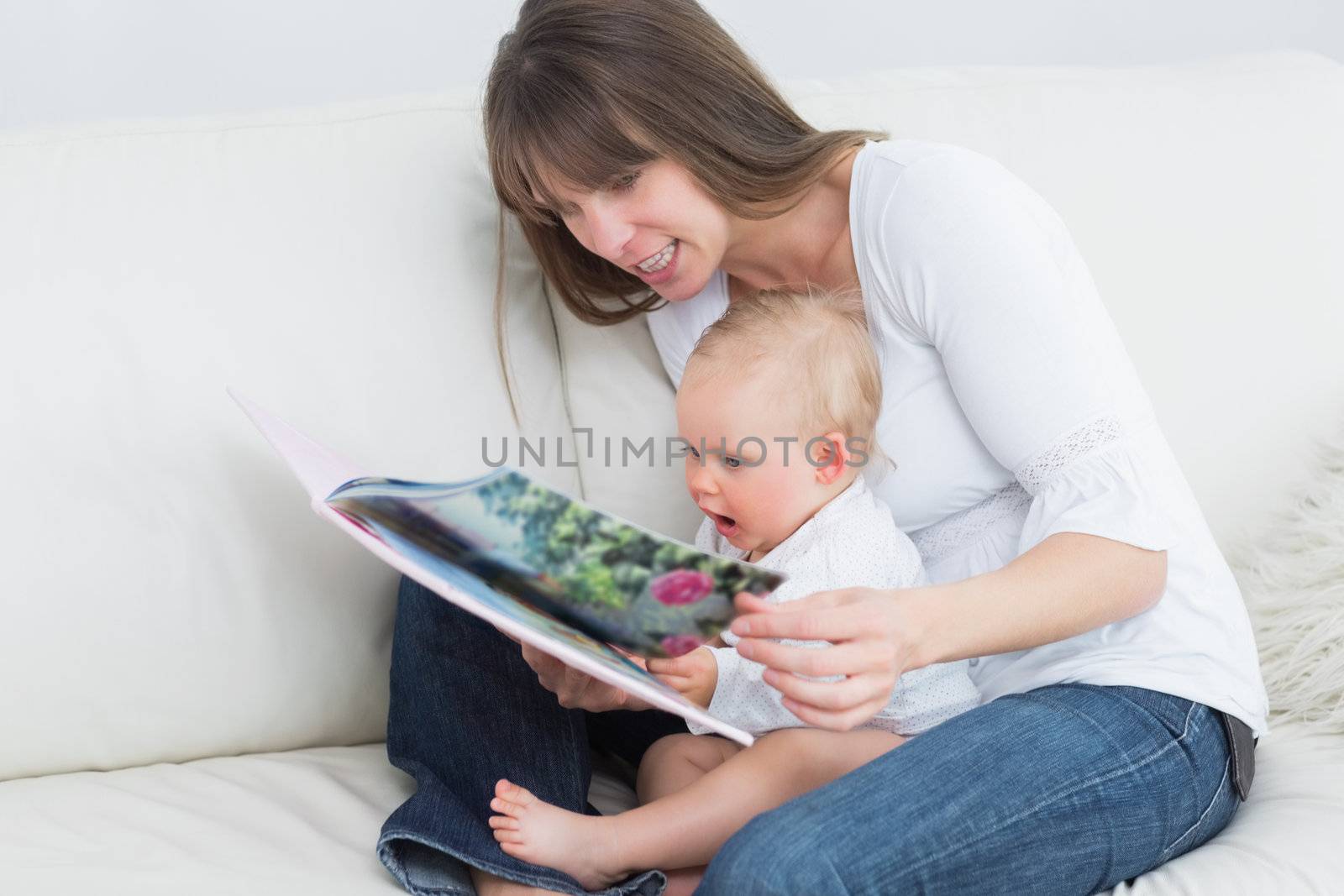 Mother reading a book with a baby in living room