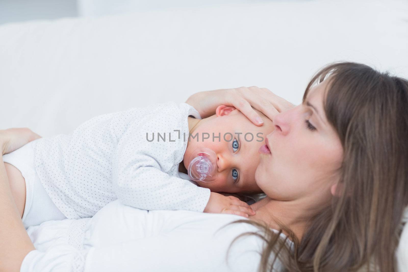 Baby lying on his mother in living room