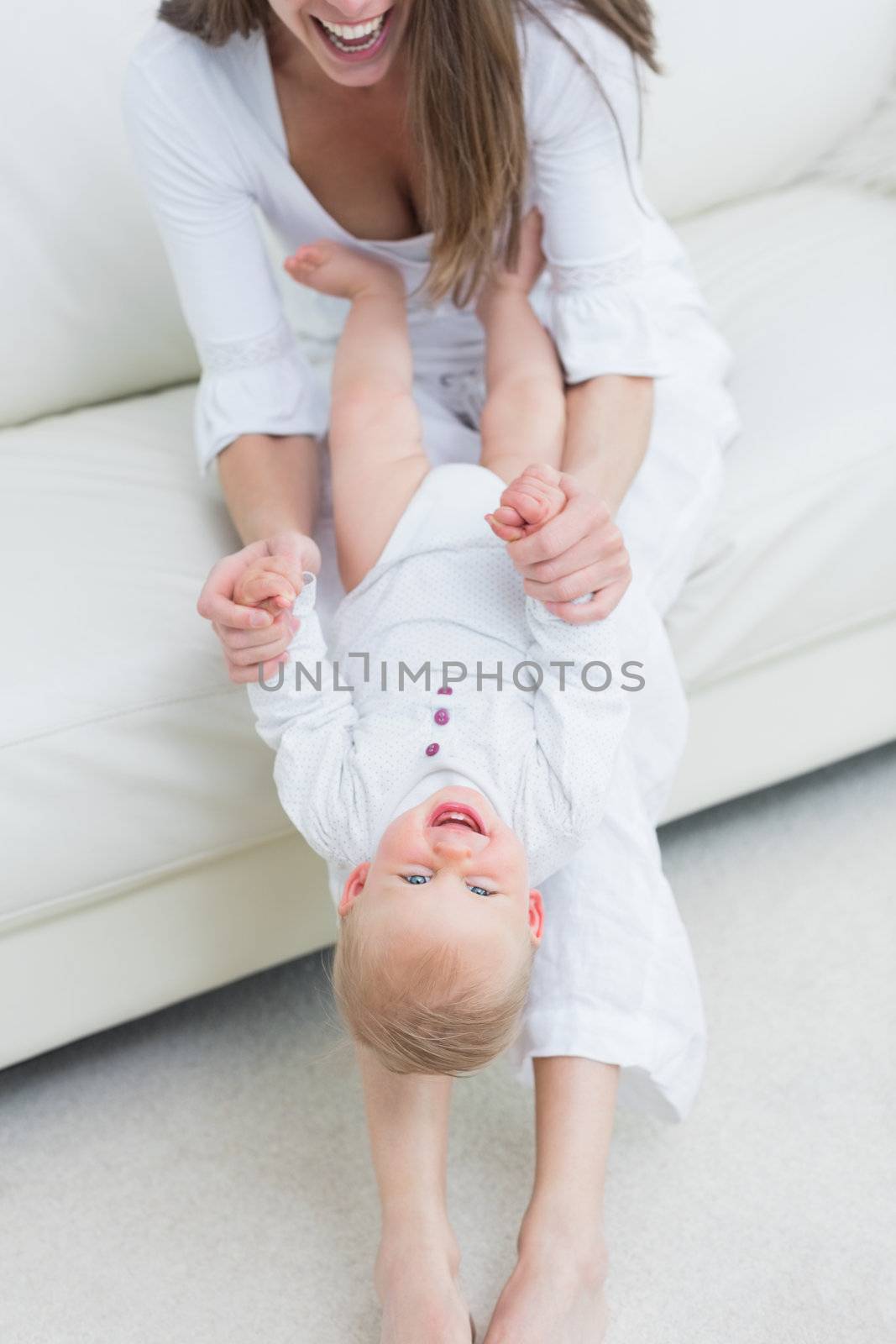 Mother sitting on a sofa playing with a baby in living room