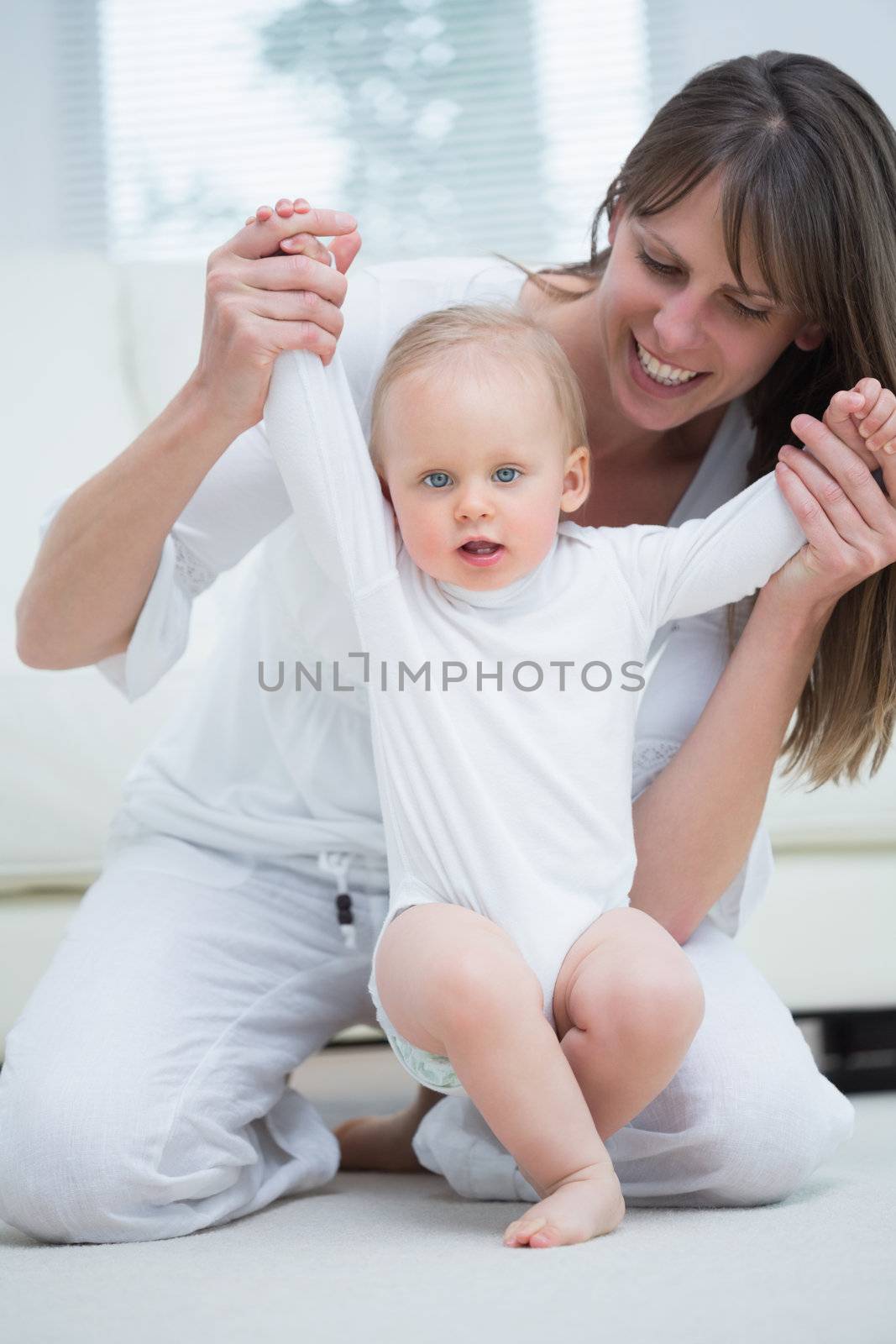 Mother raising arms of her baby in living room