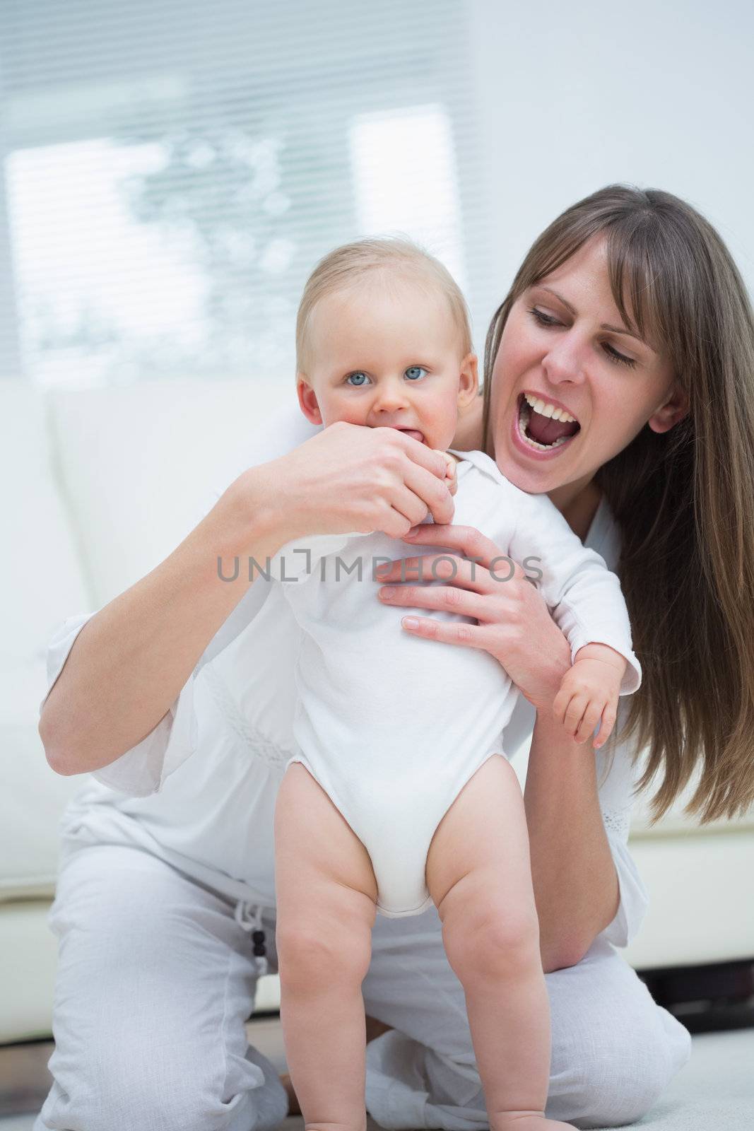 Baby standing next to his mother in living room