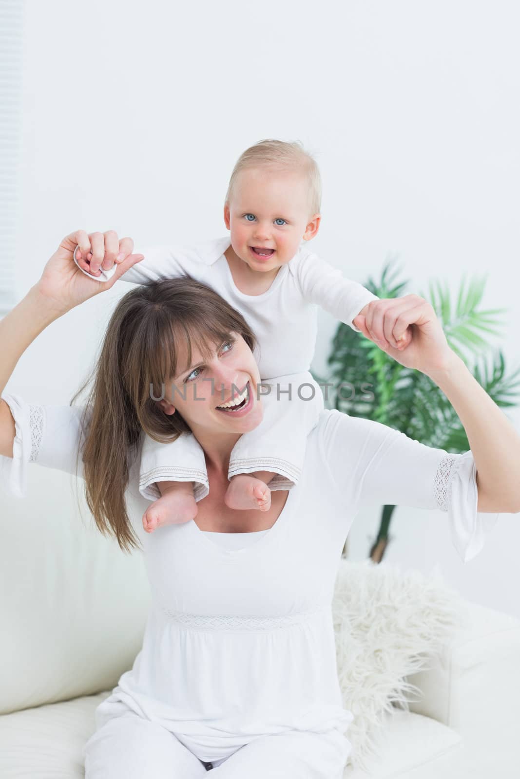 Baby sitting on shoulders of his mother by Wavebreakmedia