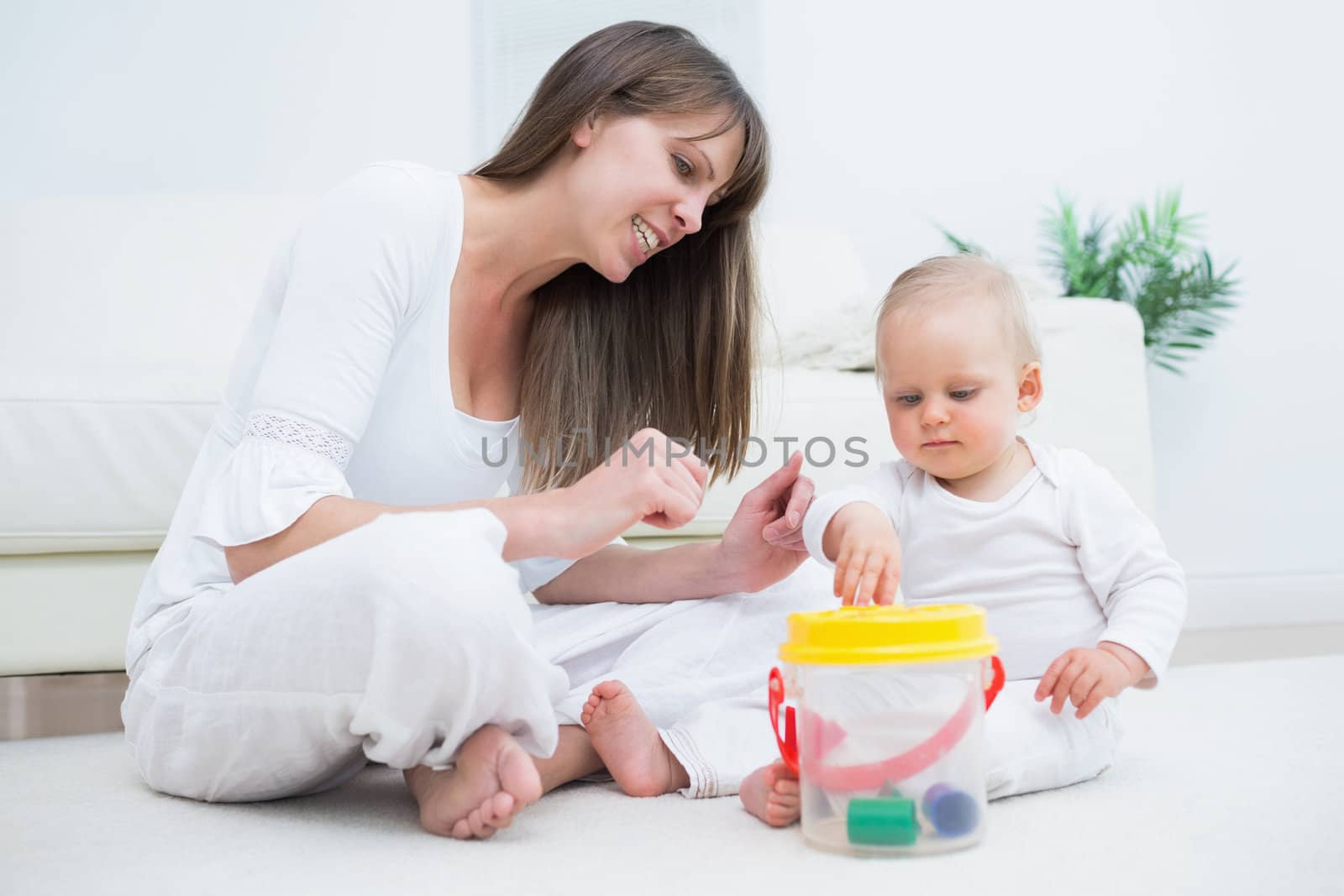 Mother sitting next to a baby playing in living room