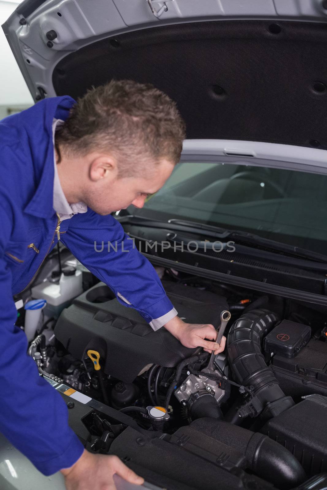 Mechanic repairing an engine with a spanner in a garage