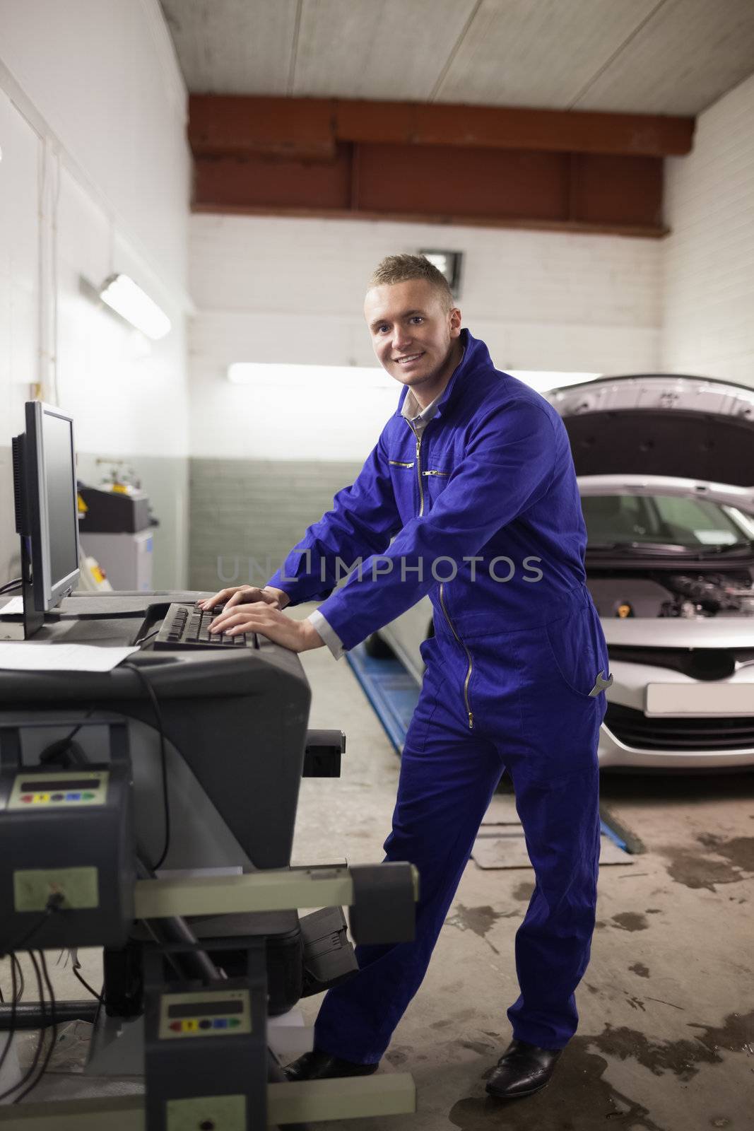 Mechanic using a computer while smiling in a garage