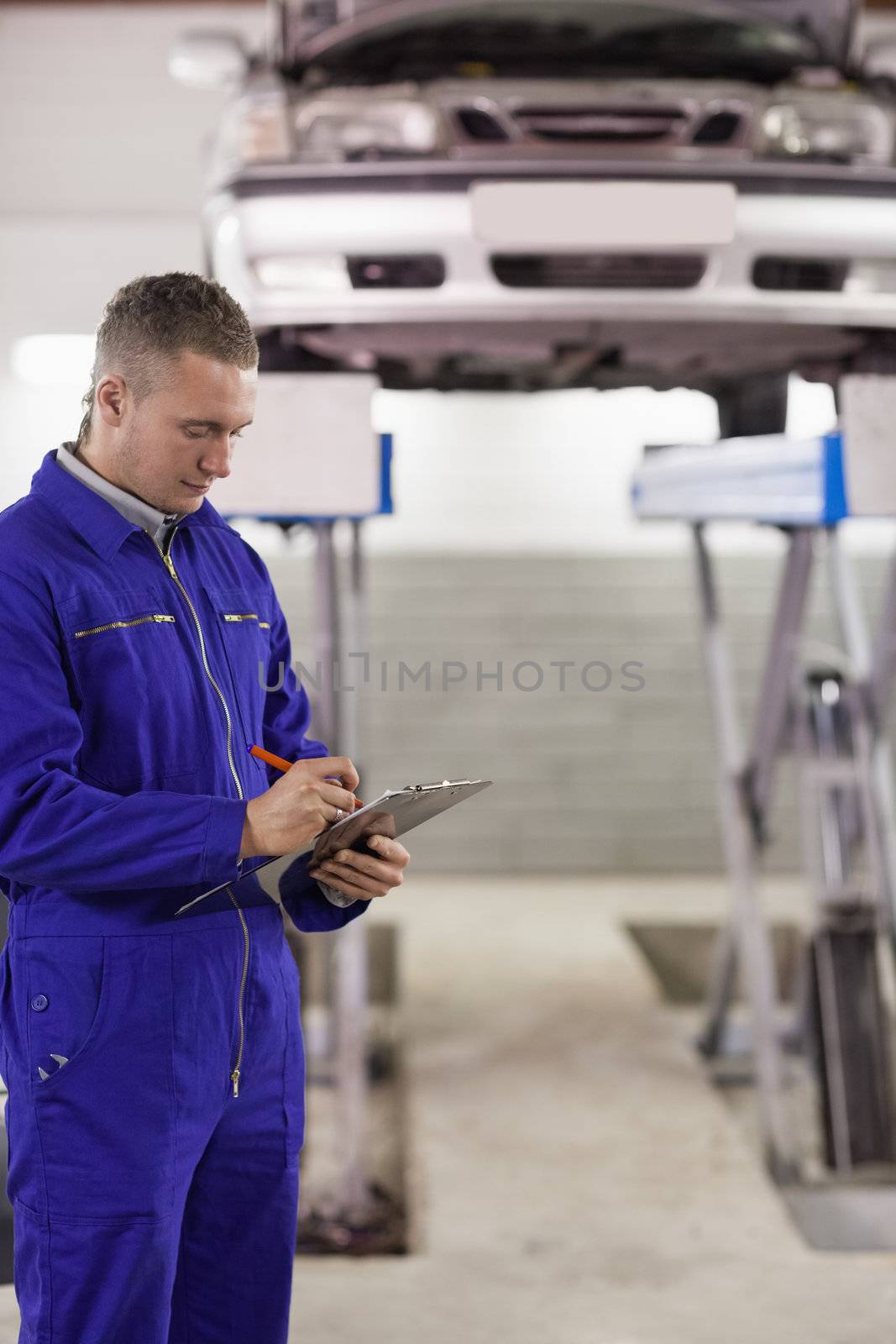 Concentrated mechanic holding a clipboard by Wavebreakmedia