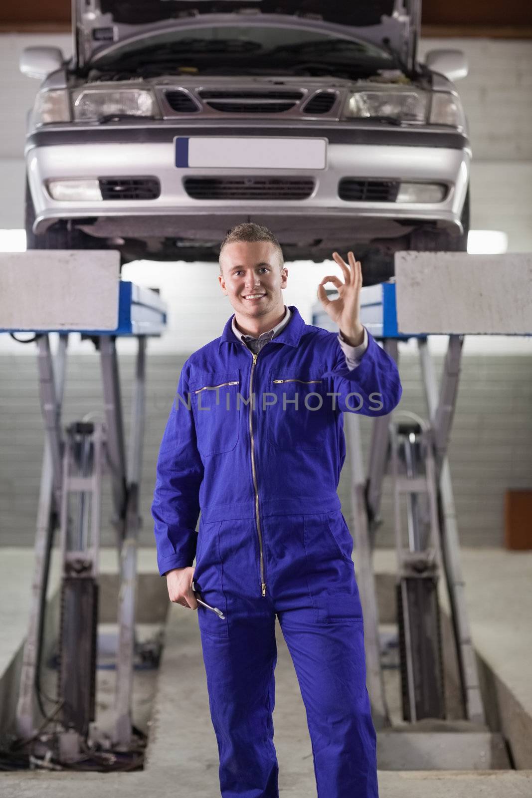 Mechanic standing doing a gesture with his fingers in a garage