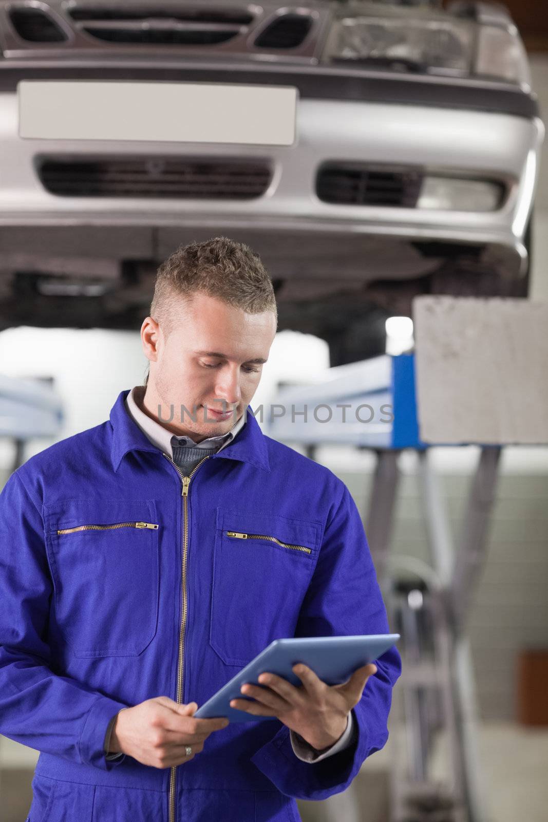 Mechanic looking at a tablet computer while holding it in a garage