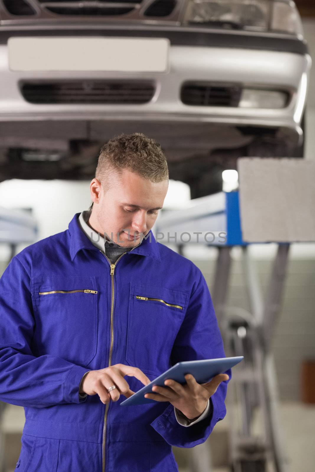 Concentrated mechanic holding a tablet computer in a garage