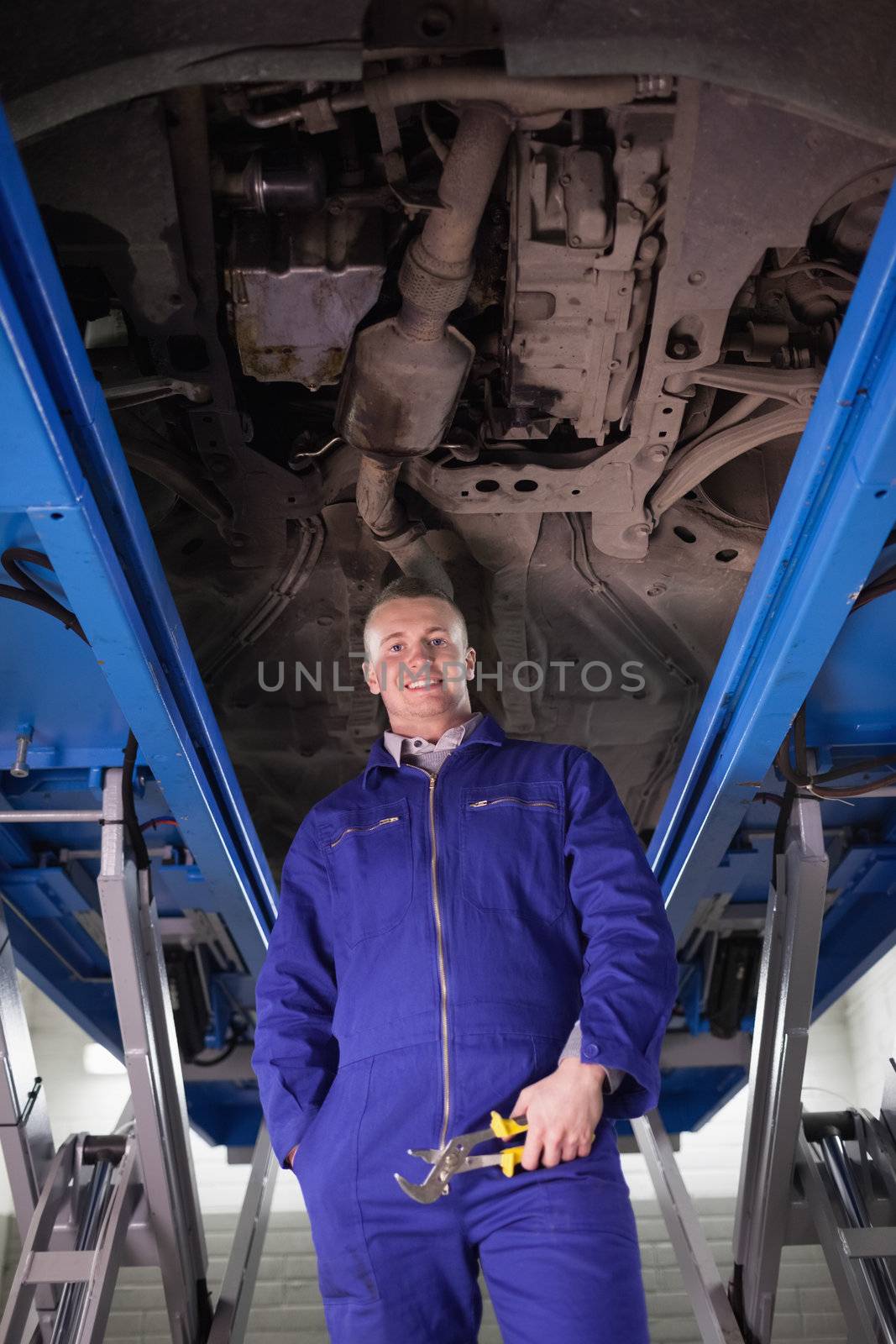 Mechanic standing up below a car in a garage