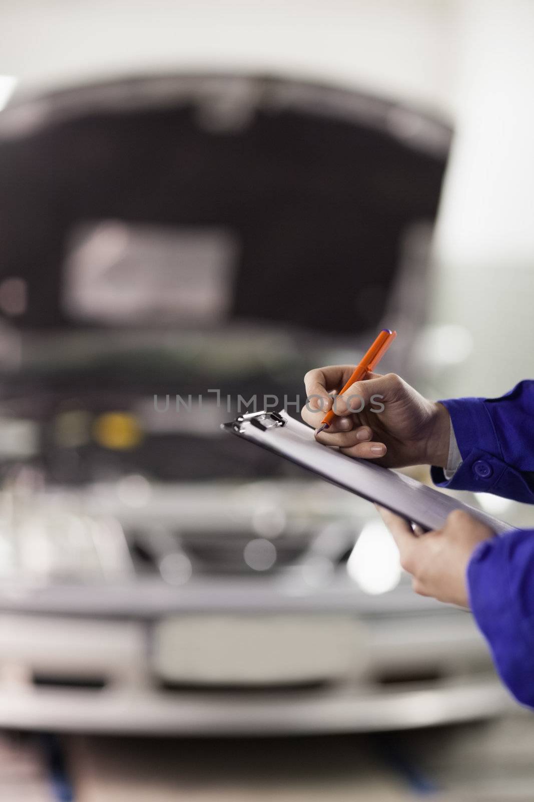 Focus on a man writing on a clipboard in a garage