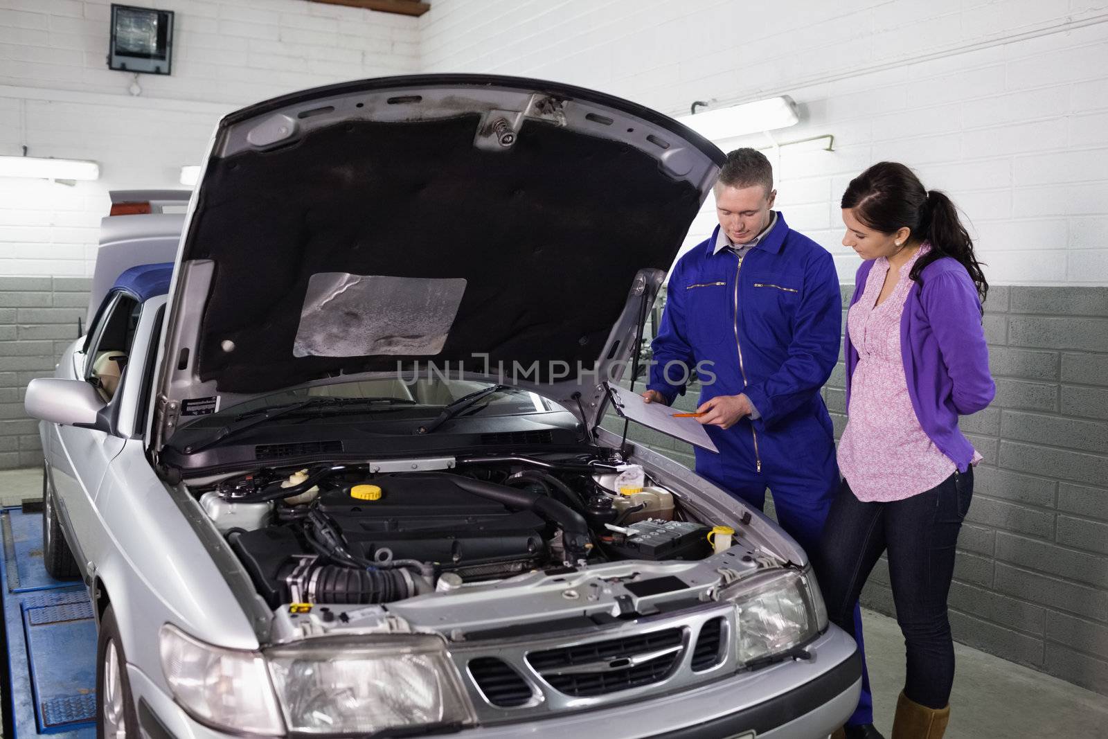 Mechanic showing a clipboard to a woman in a garage