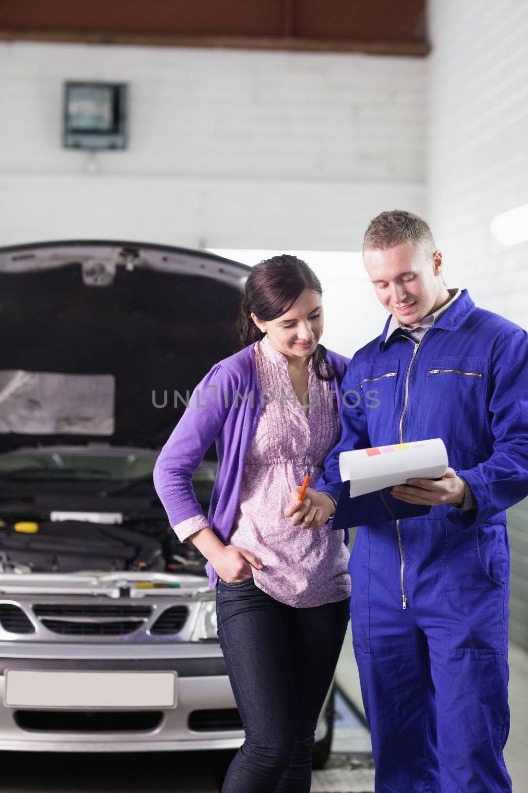 Mechanic showing a paper in a clipboard to a client in a garage