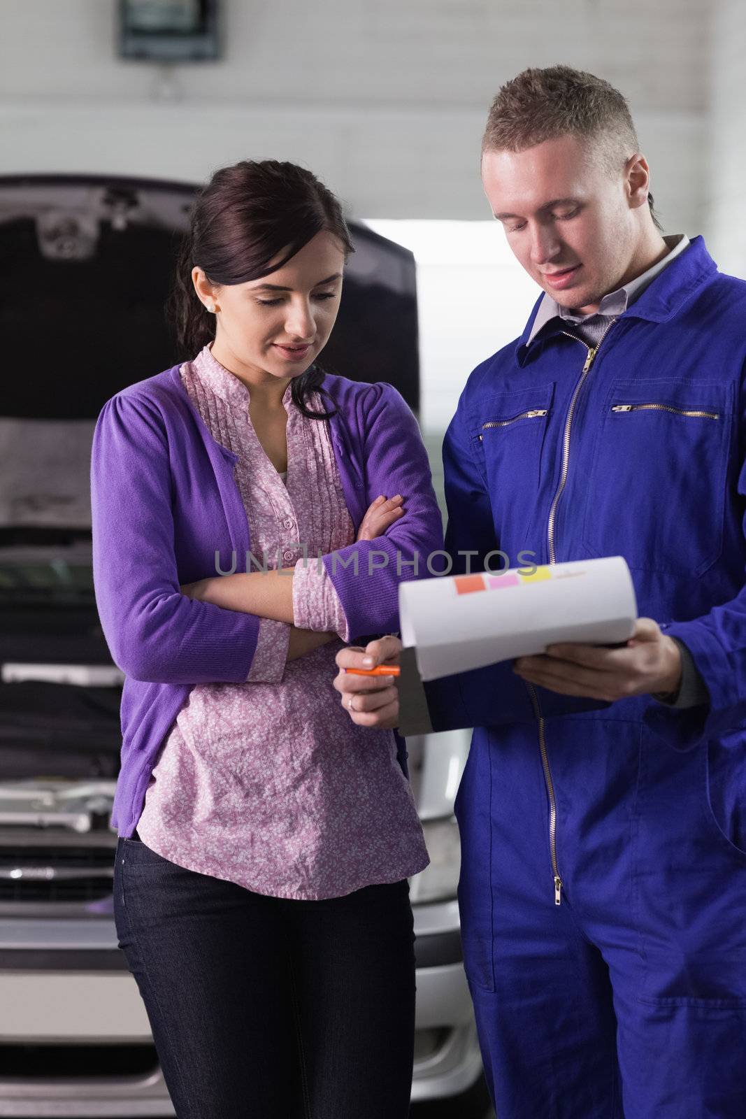 Mechanic showing the quotation to a woman in a garage