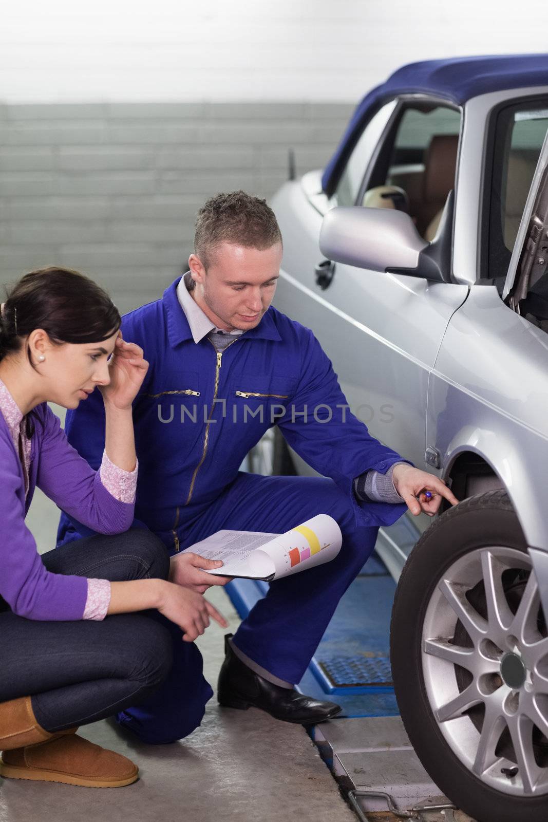 Mechanic touching the car wheel while looking at it in a garage