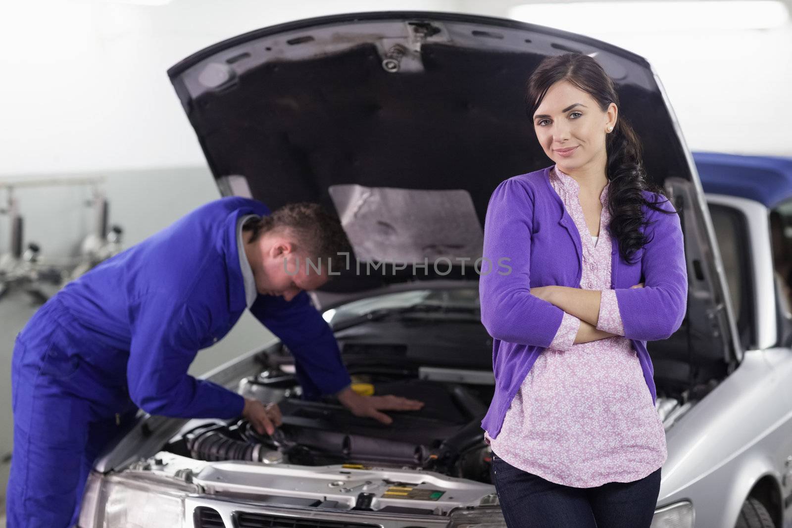 Woman leaning on a car next to a mechanic in a garage