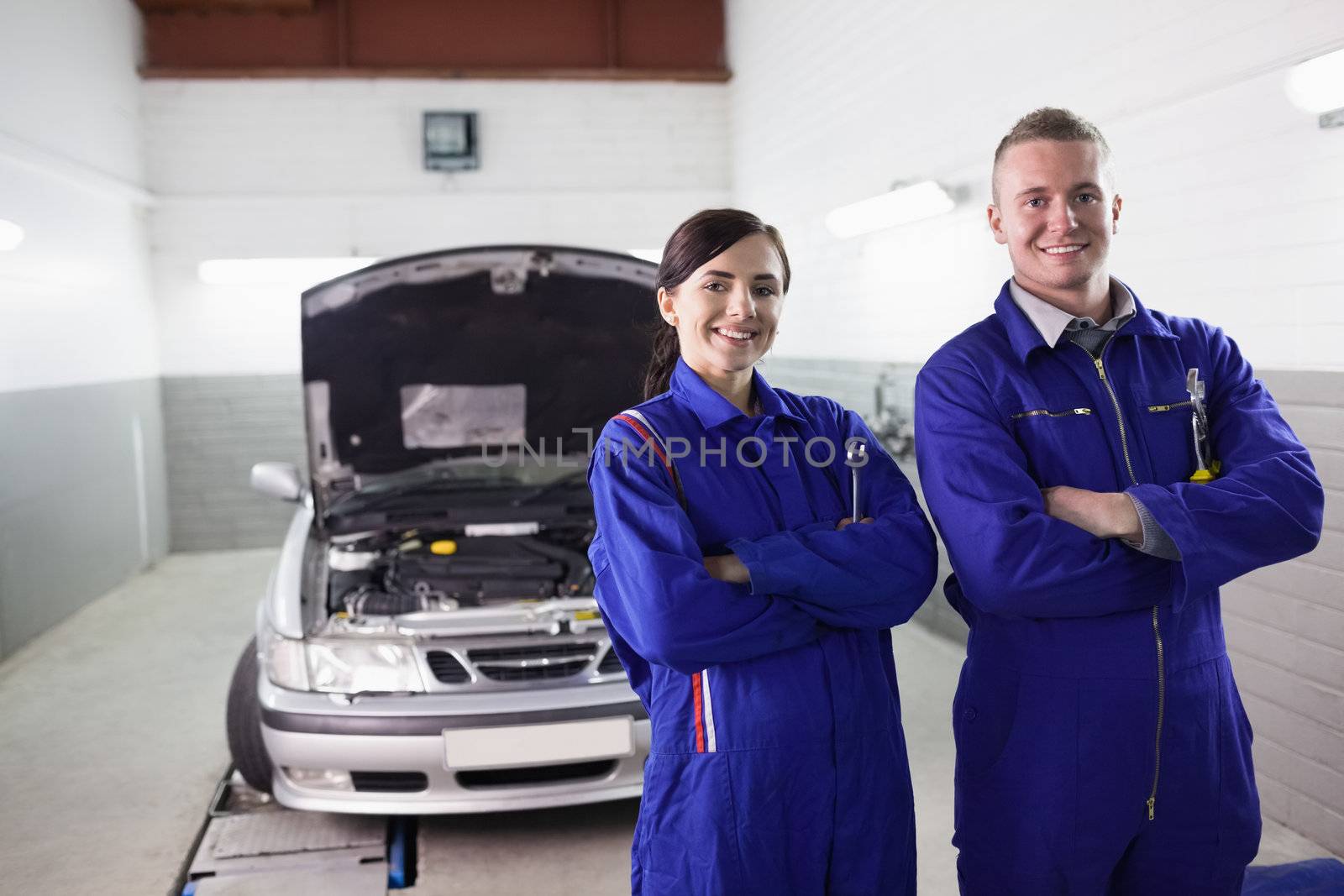 Smiling mechanics with arms crossed in a garage