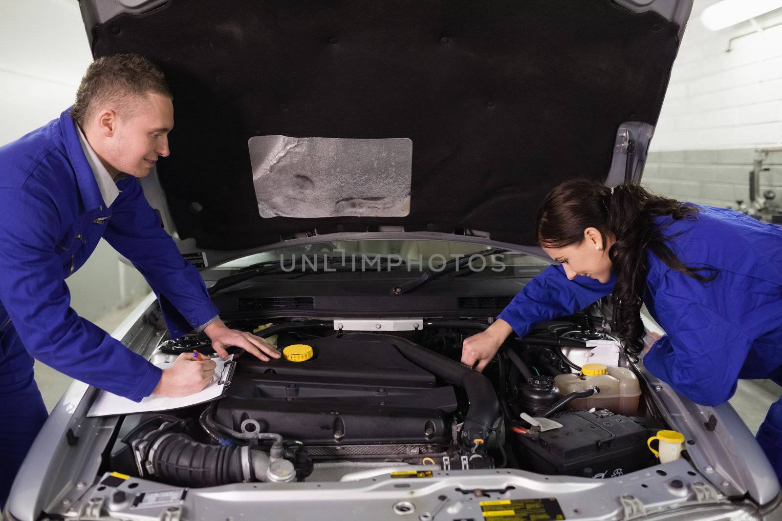 Mechanics checking a car engine in a garage