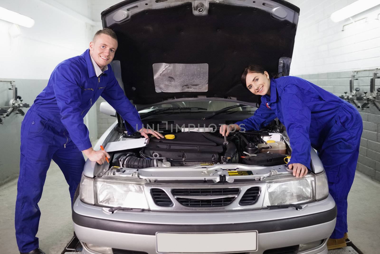 Mechanics leaning on a car in a garage