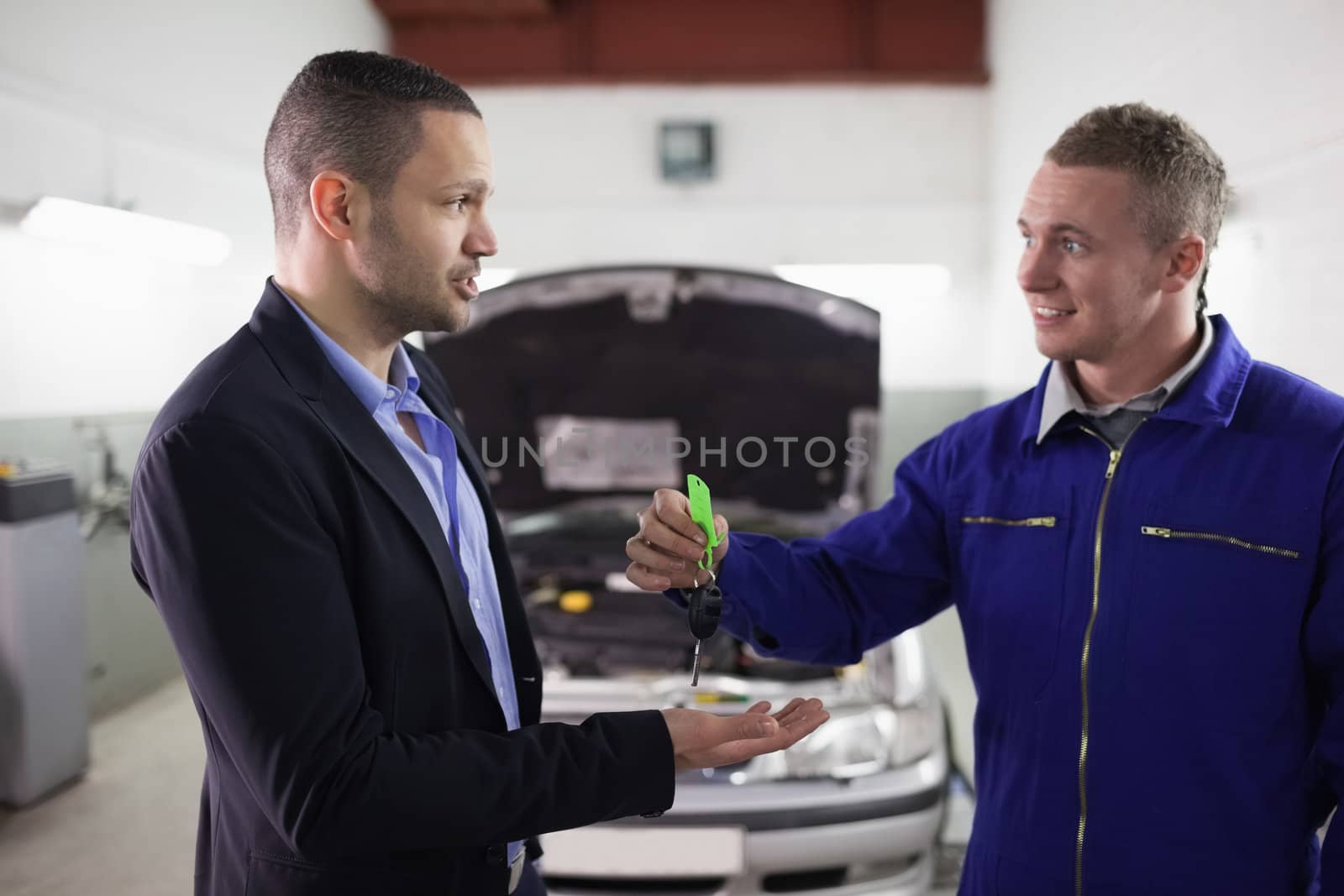 Mechanic giving car key to a man in a garage