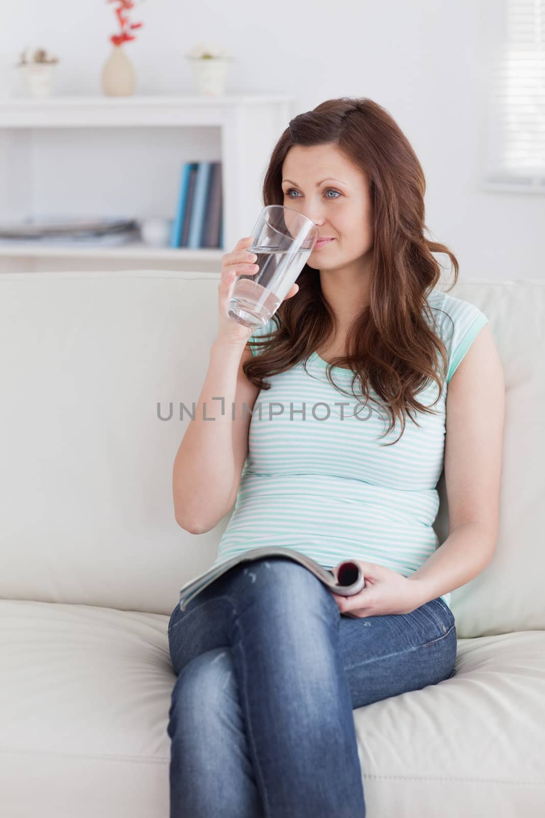 Woman drinking while sitting on a sofa in a living room