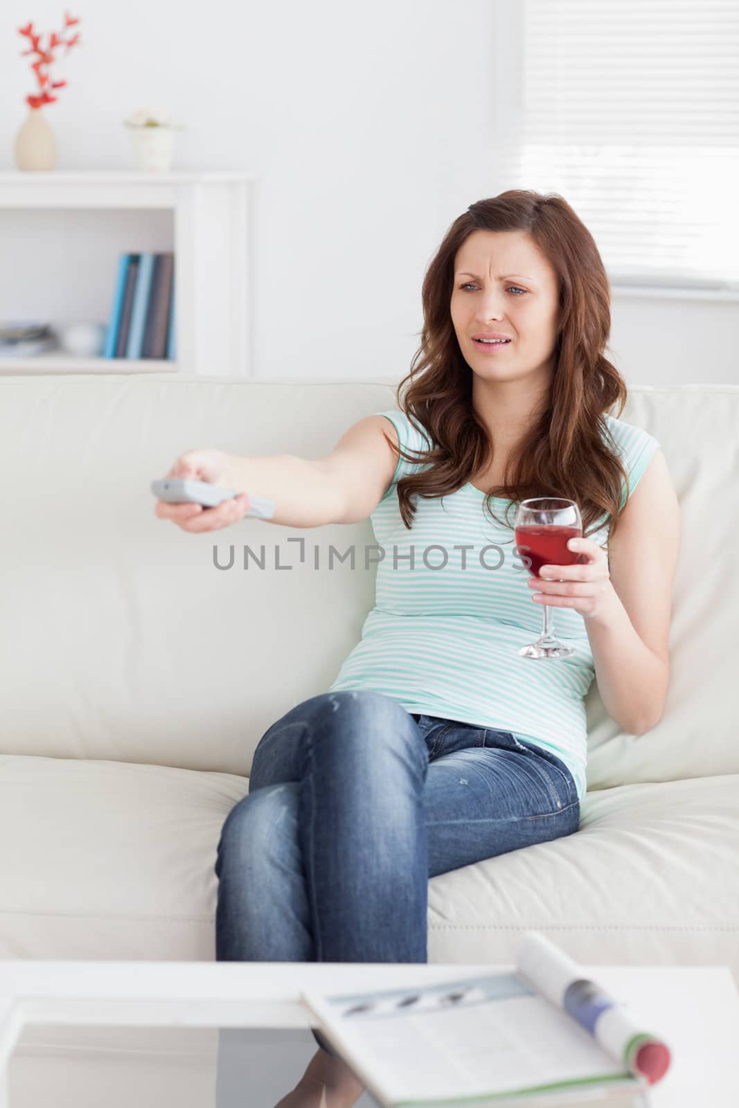 Woman pressing a remote control while sitting in a living room