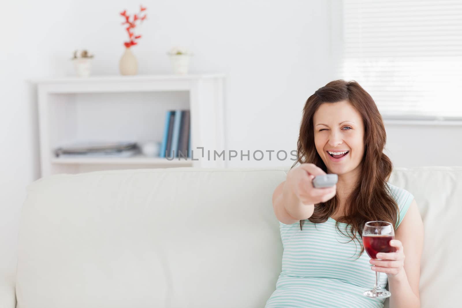 Smiling woman pressing a remote control in a living room