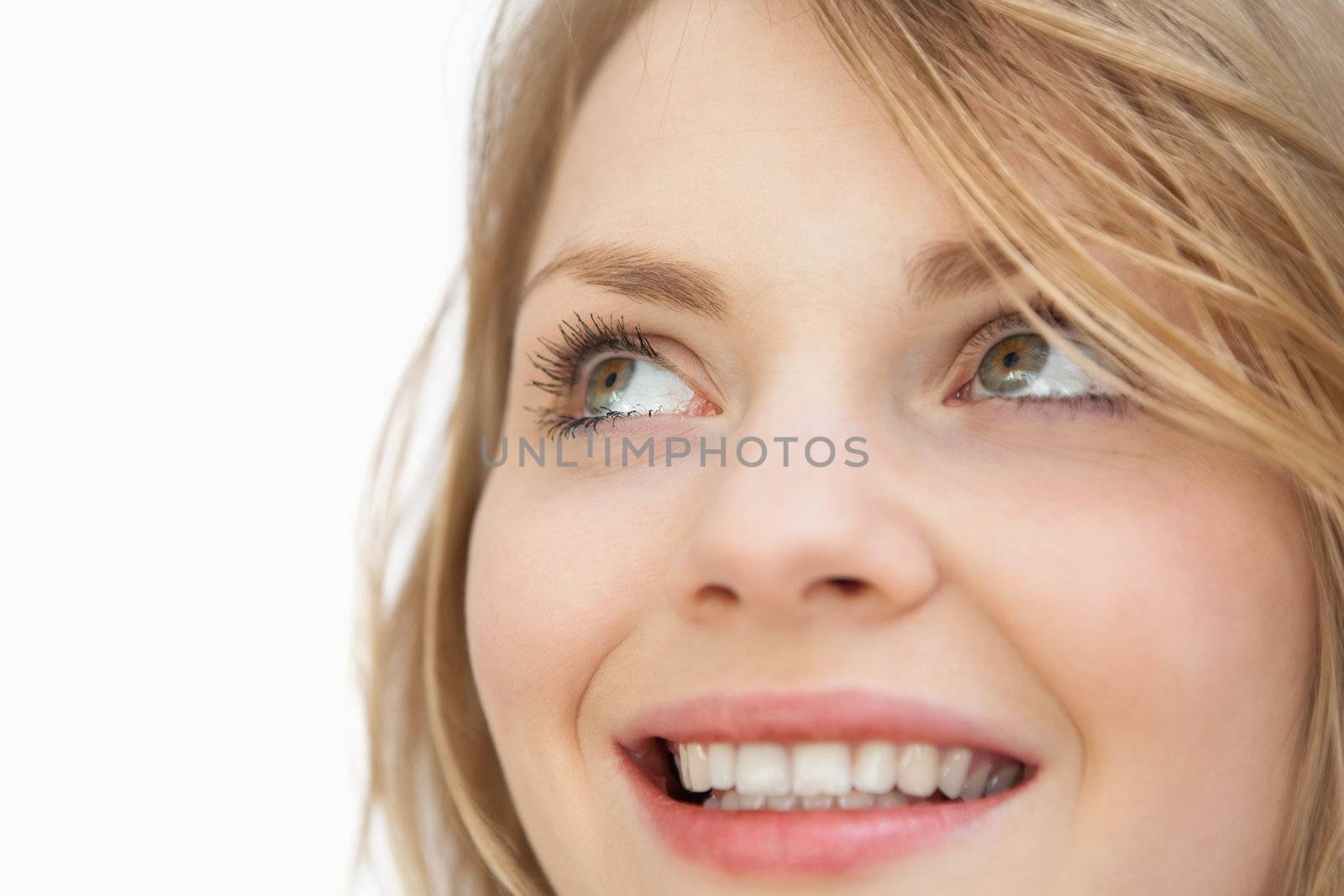 Woman looking up while smiling against a white background