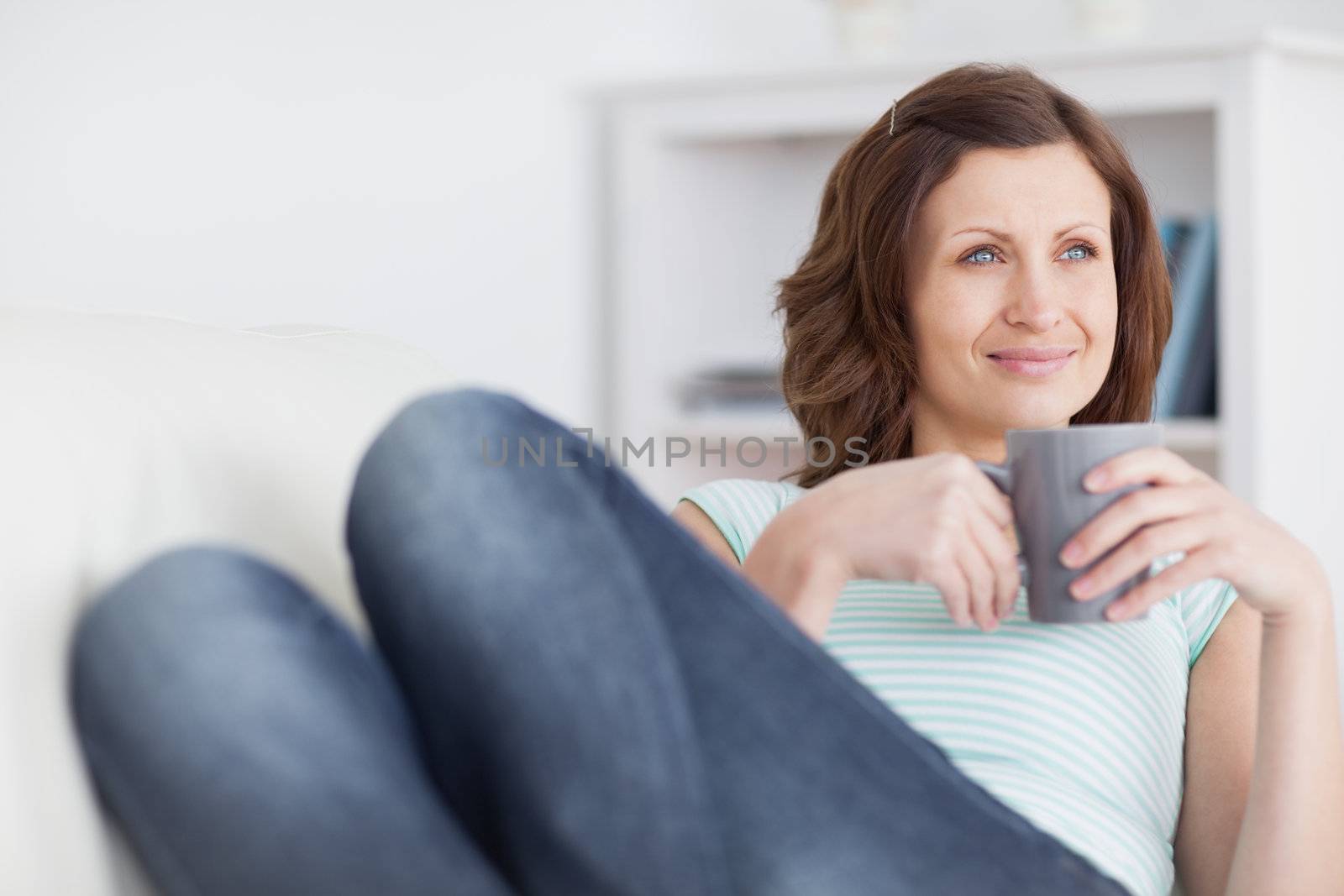 Woman looking away while holding a mug in a living room