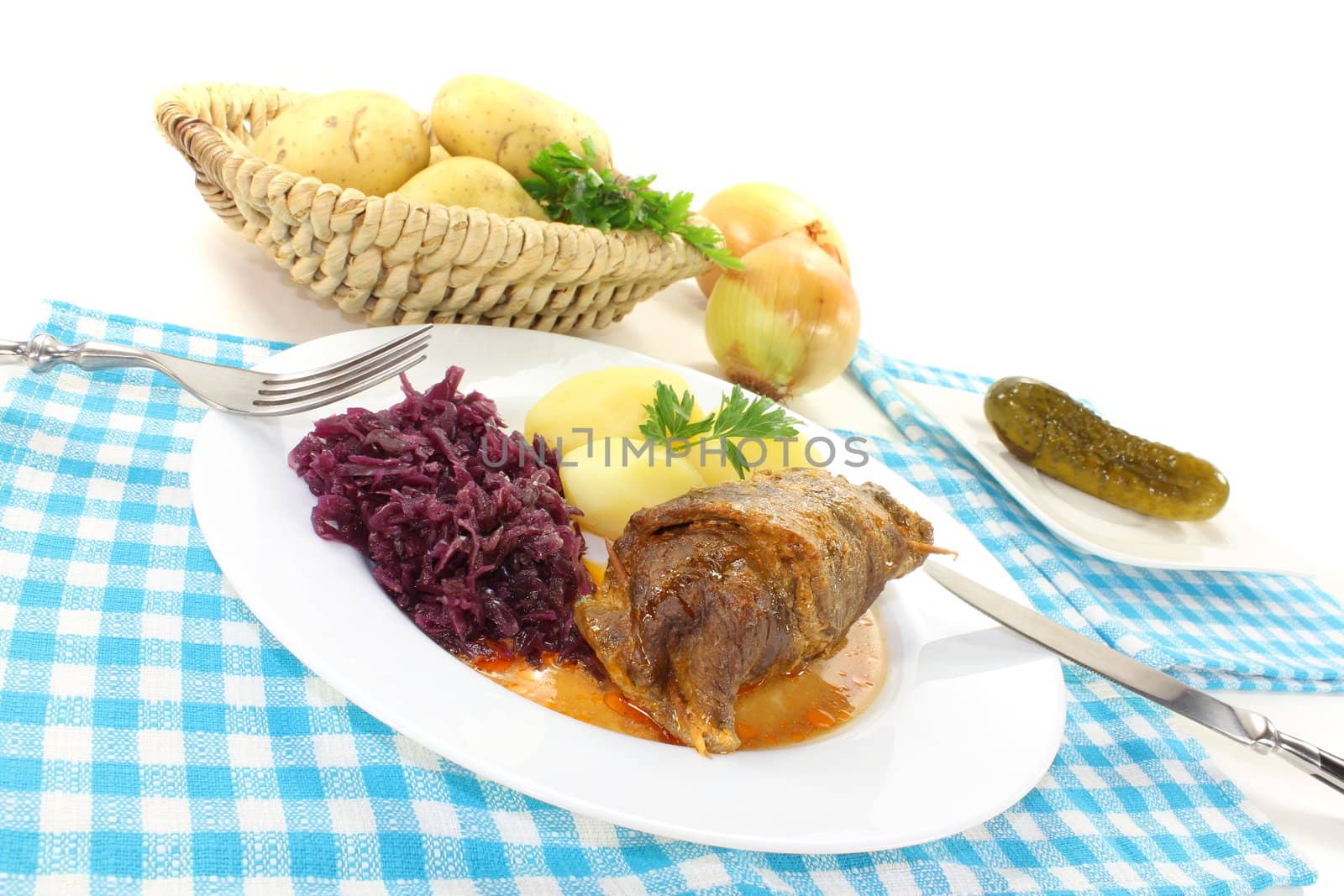 Beef roulade with potatoes and red cabbage on a light background